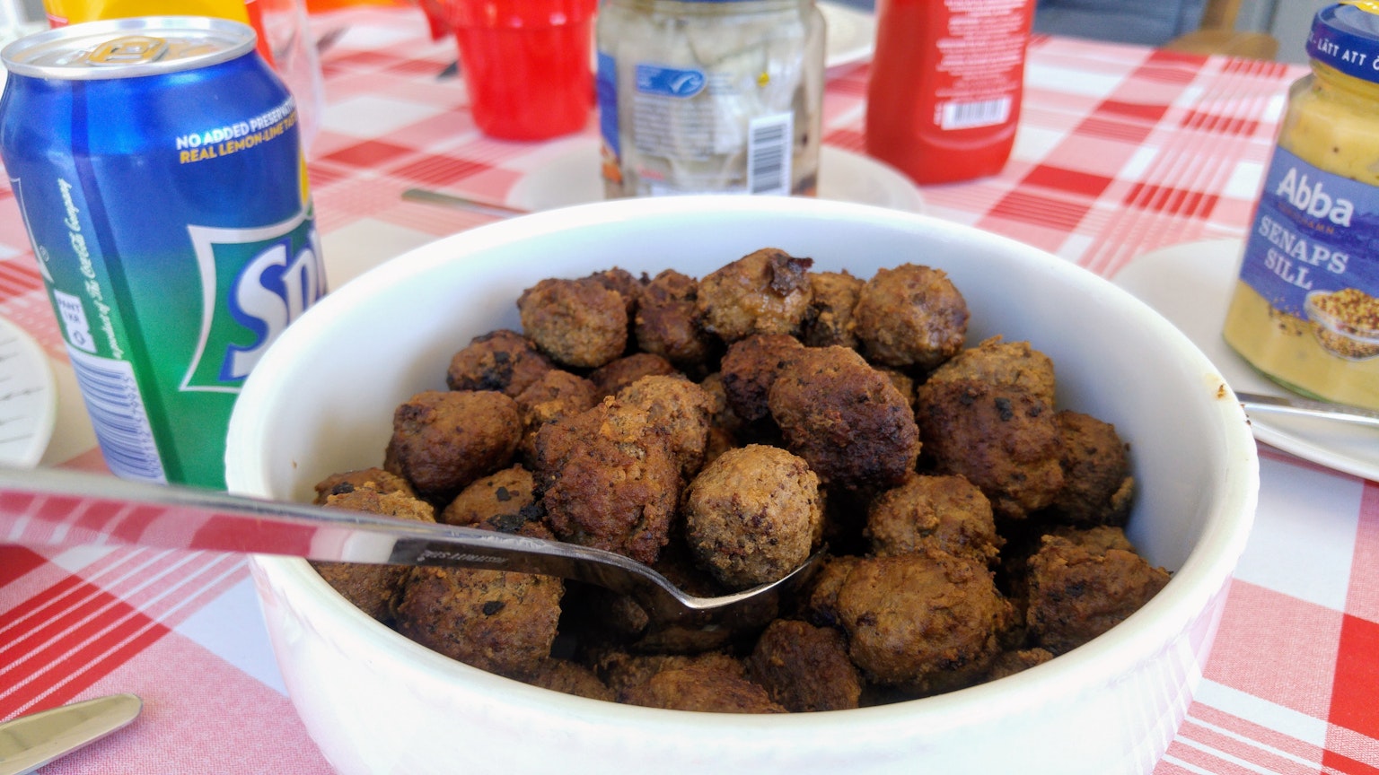 Ciotola di polpette fritte con un cucchiaio circondata da bevande e barattoli di condimenti