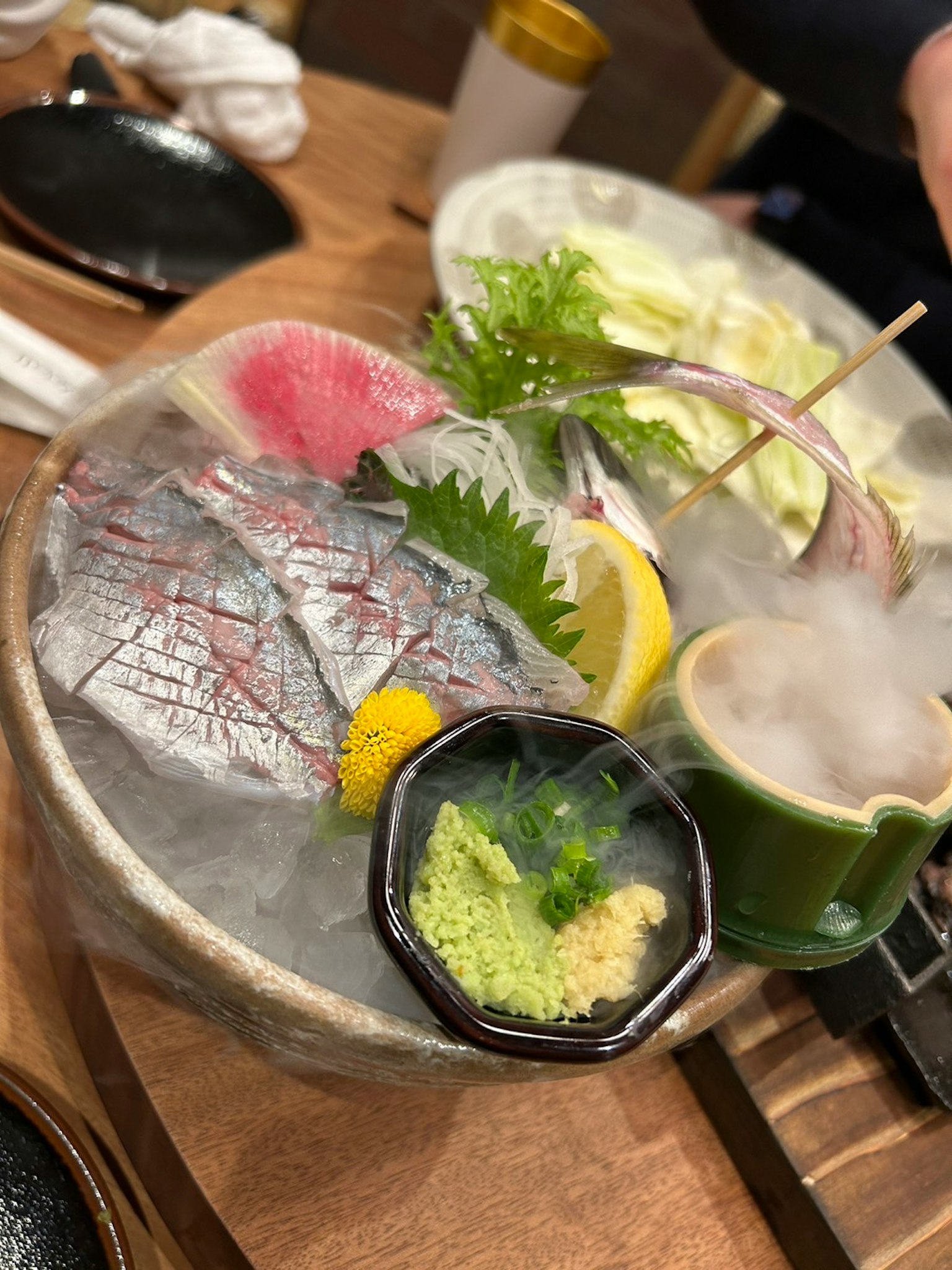 Một đĩa sashimi nhiều màu sắc với cá tươi được trang trí bằng wasabi và chanh trên đá