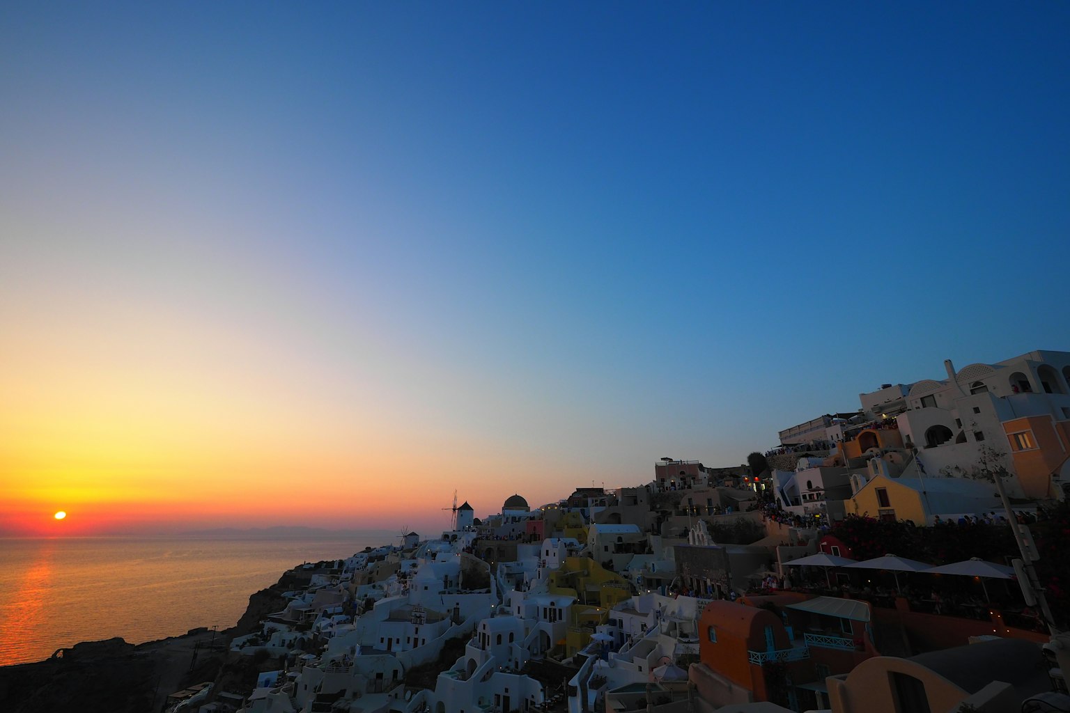 Beeindruckender Sonnenuntergang über Santorin mit weißen Gebäuden am Hang