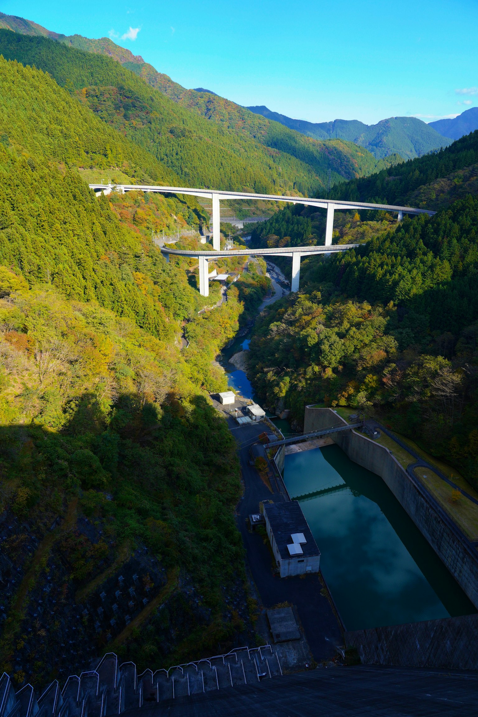 一座跨越河流的高架橋的美景，周圍環繞著郁郁蔥蔥的綠色山脈