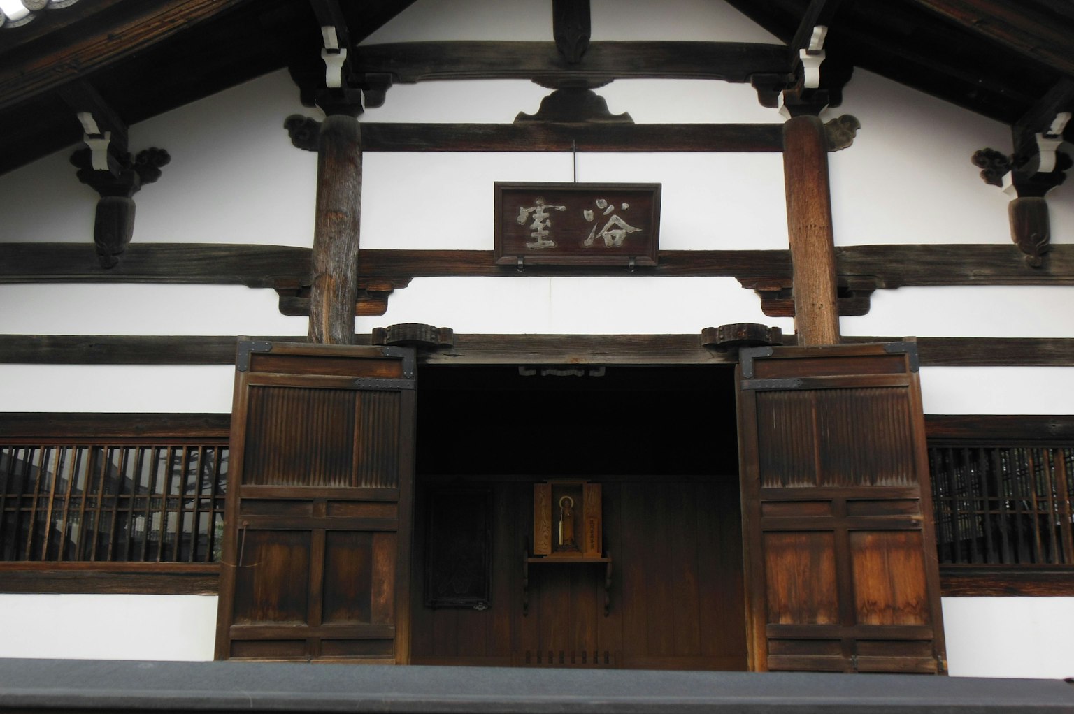 Entrée d'un bâtiment japonais traditionnel avec des portes en bois et des murs blancs
