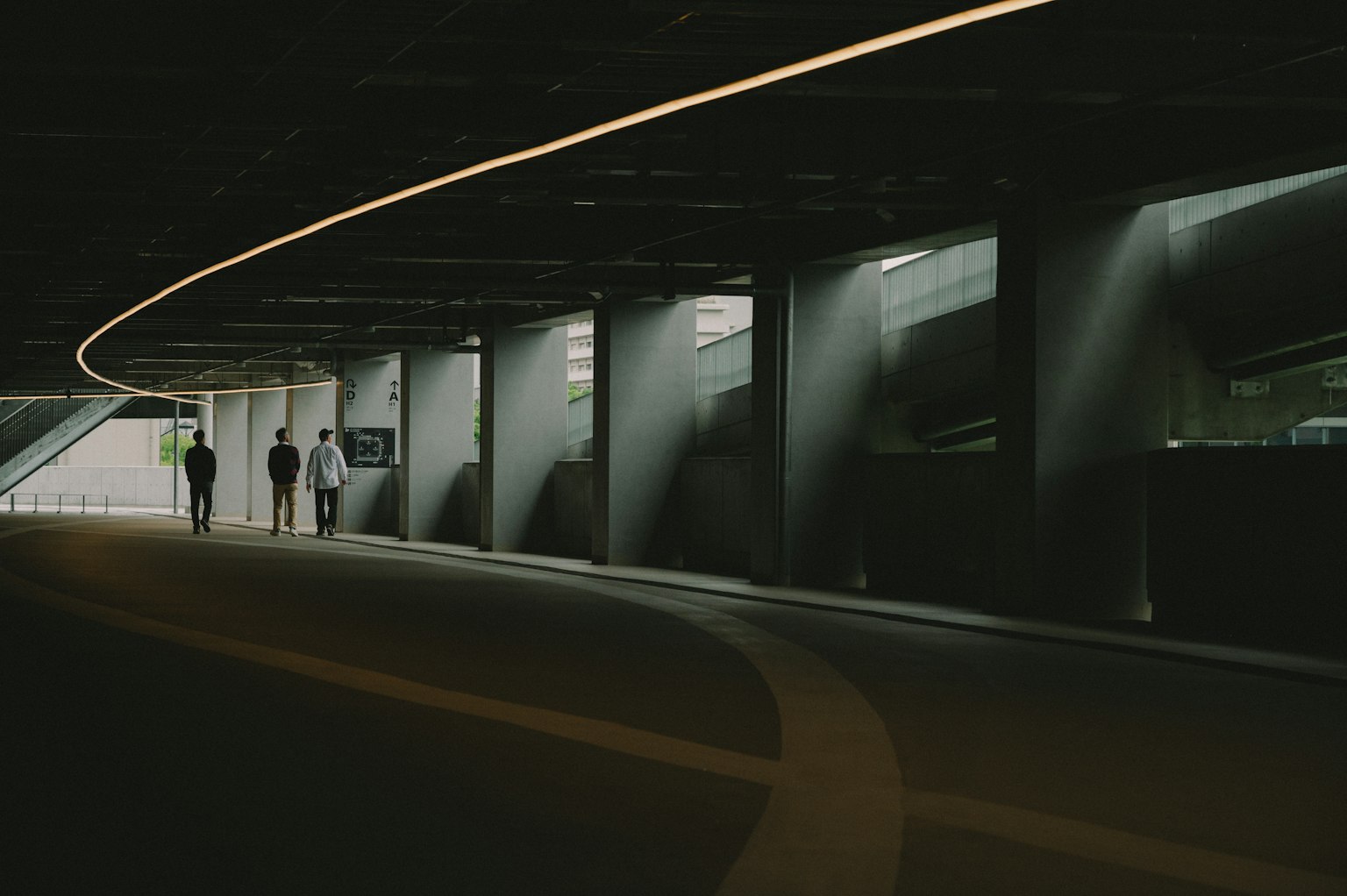 Persone che camminano in un tunnel scuro con illuminazione curva liscia