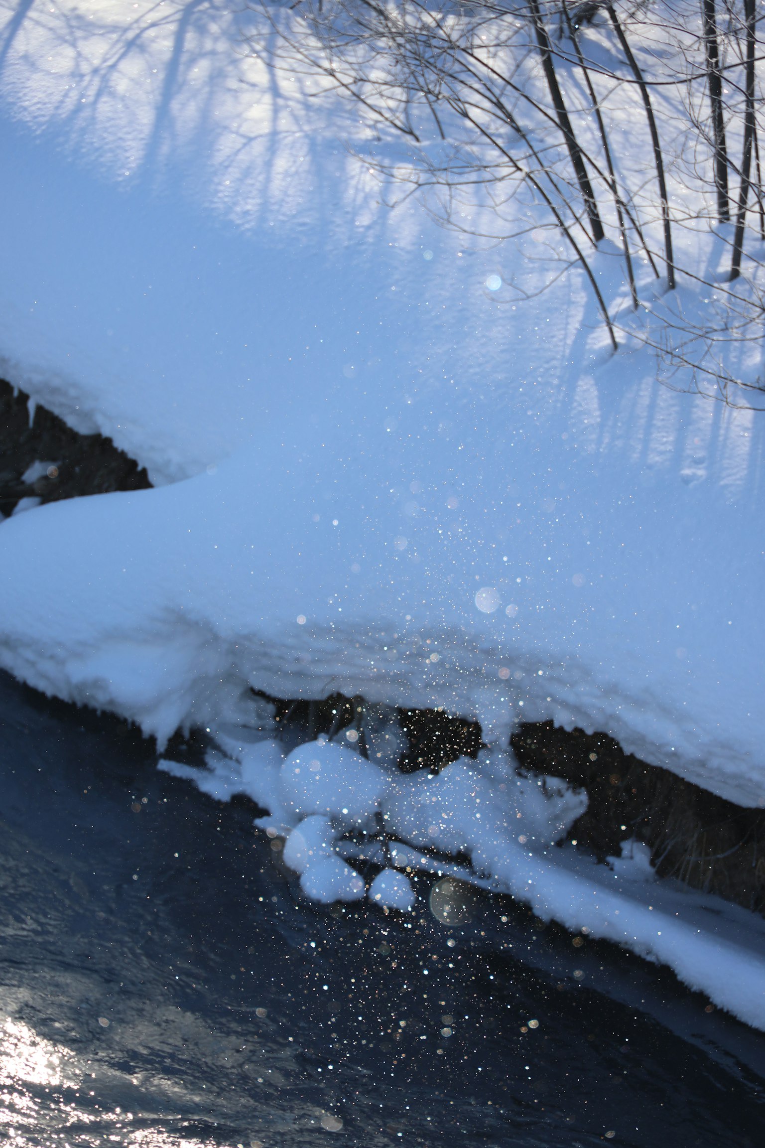Snow-covered riverbank with splashing water