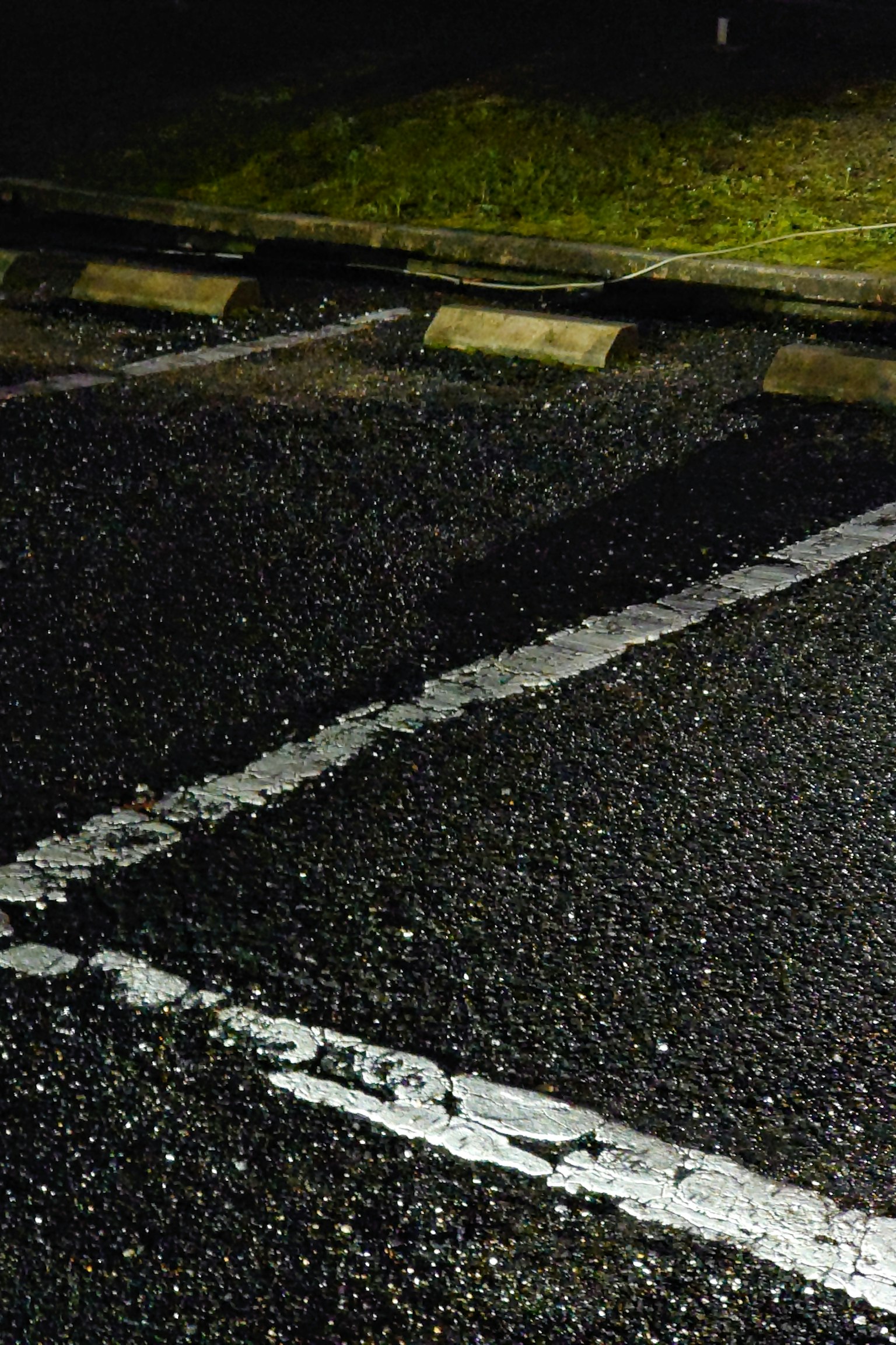 Une section d'un parking sombre montrant l'asphalte et des lignes blanches
