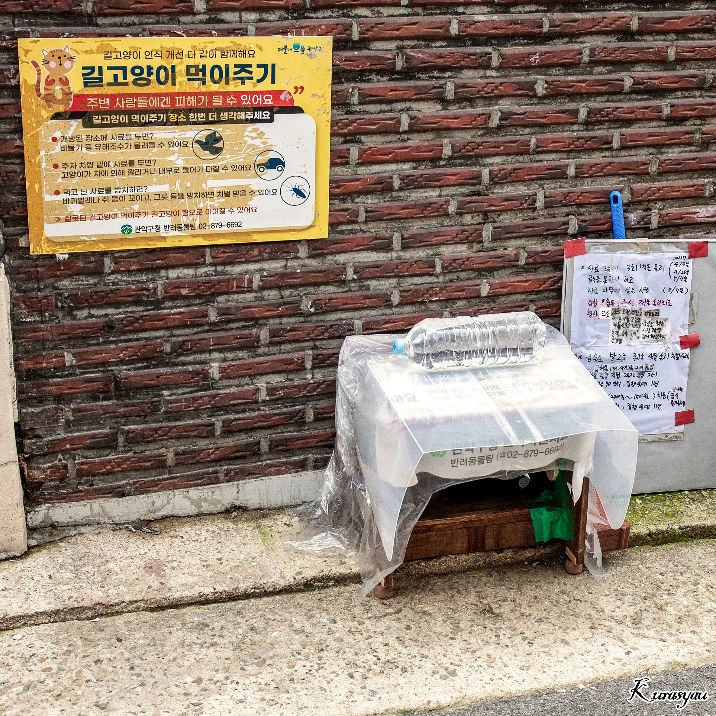 レンガ壁の前に置かれたビニール袋と掲示板のある路地