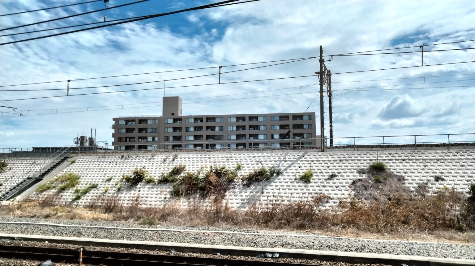 Edificio de apartamentos abandonado junto a las vías del tren bajo un cielo nublado