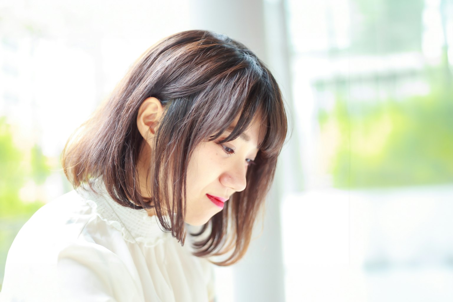 一位女性在自然光下認真思考，穿著白色服裝