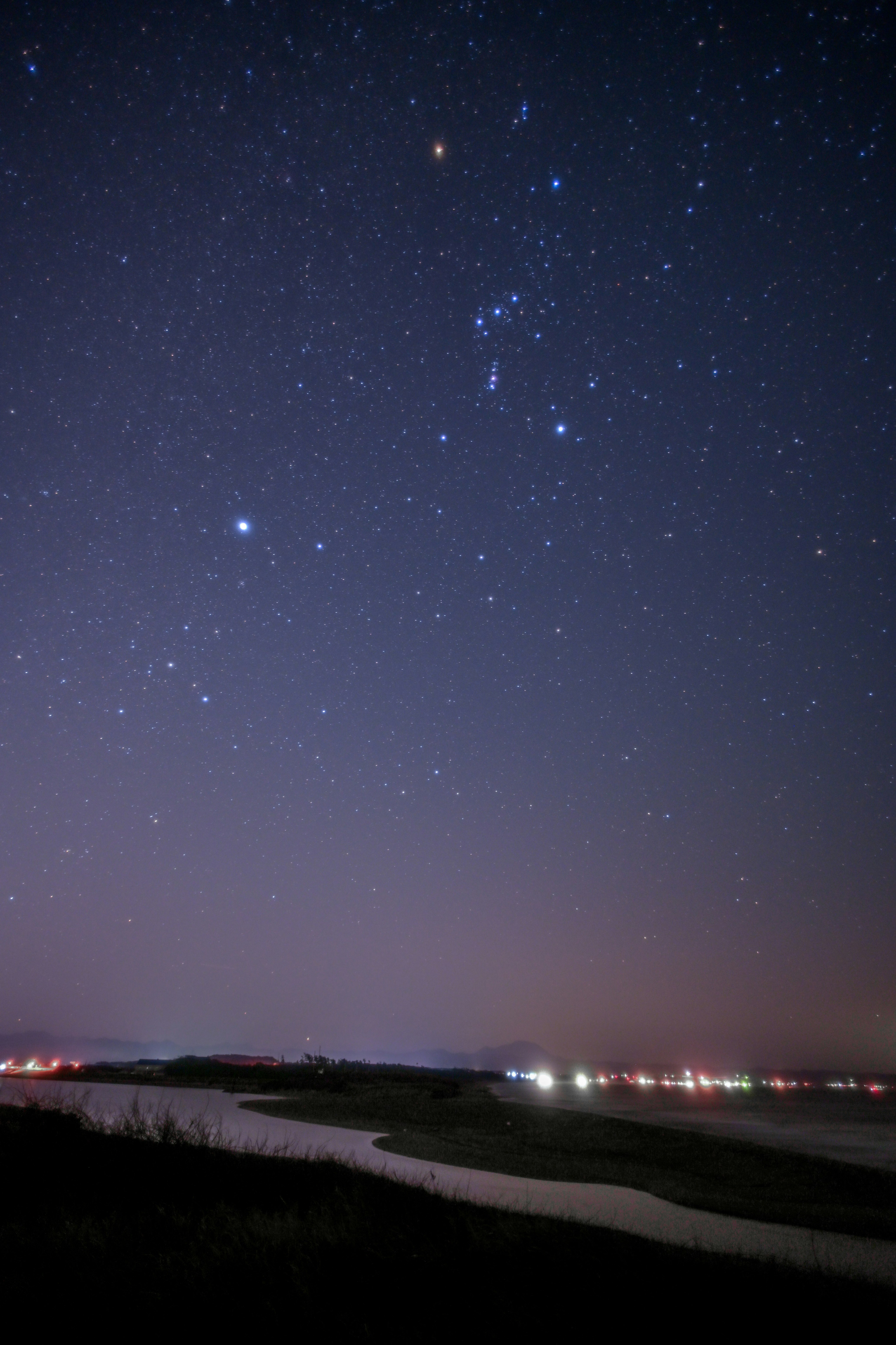 夜空に広がる星と海岸の灯りの風景