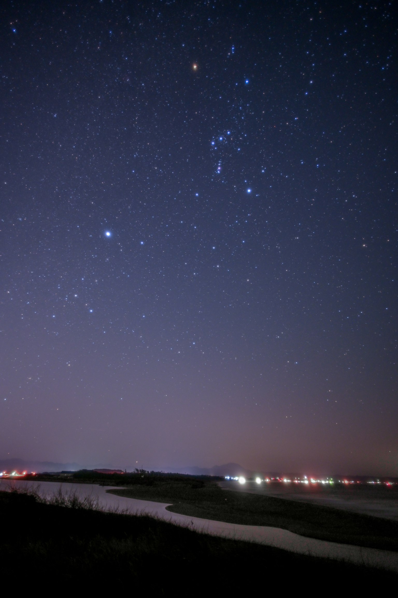 Cielo estrellado con la constelación de Orión y un río serpenteante