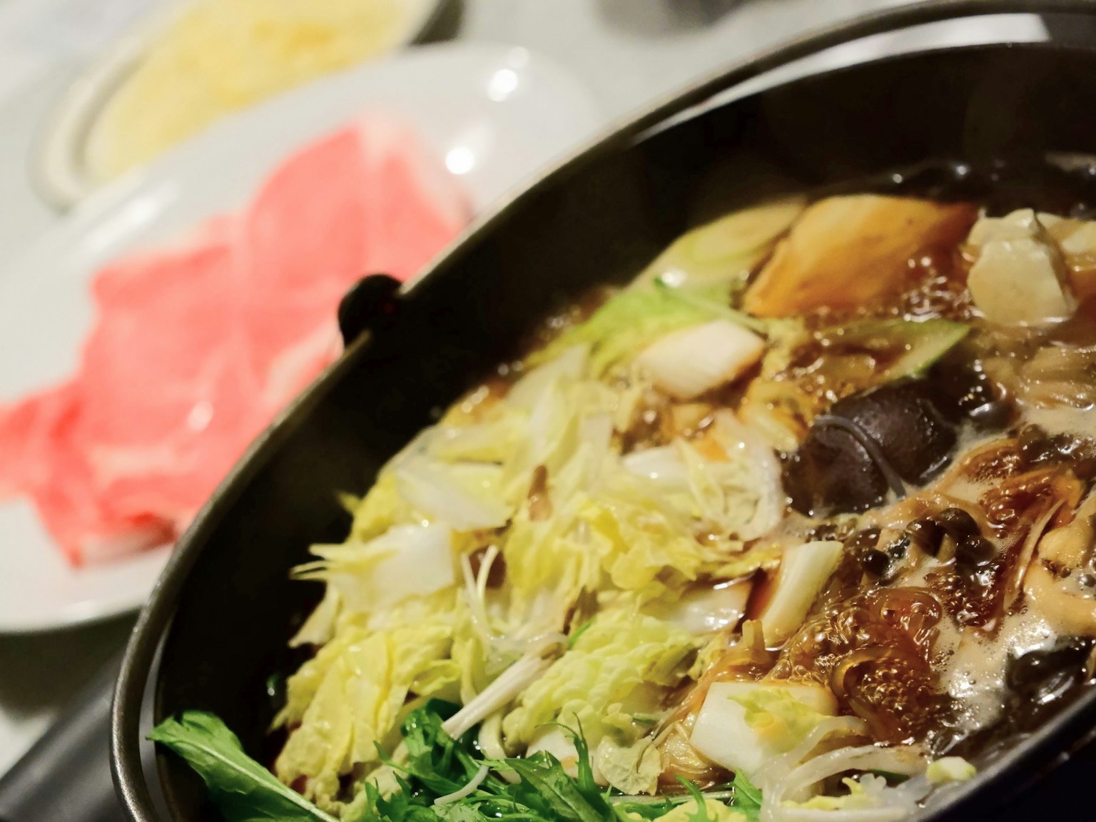 A hot pot dish filled with fresh vegetables and sliced meat