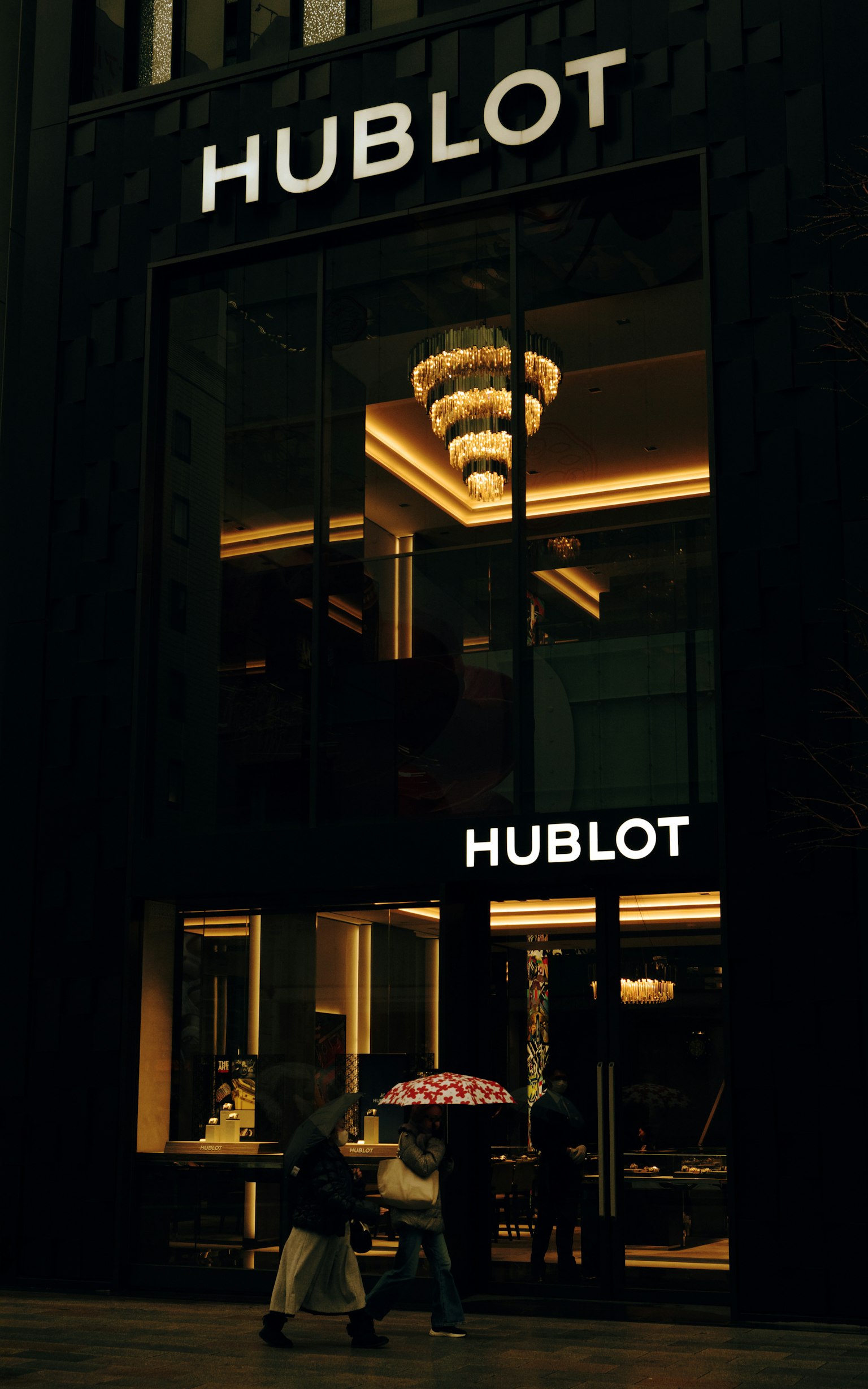 Fassade des Hublot-Geschäfts mit Besuchern, die einen Regenschirm halten