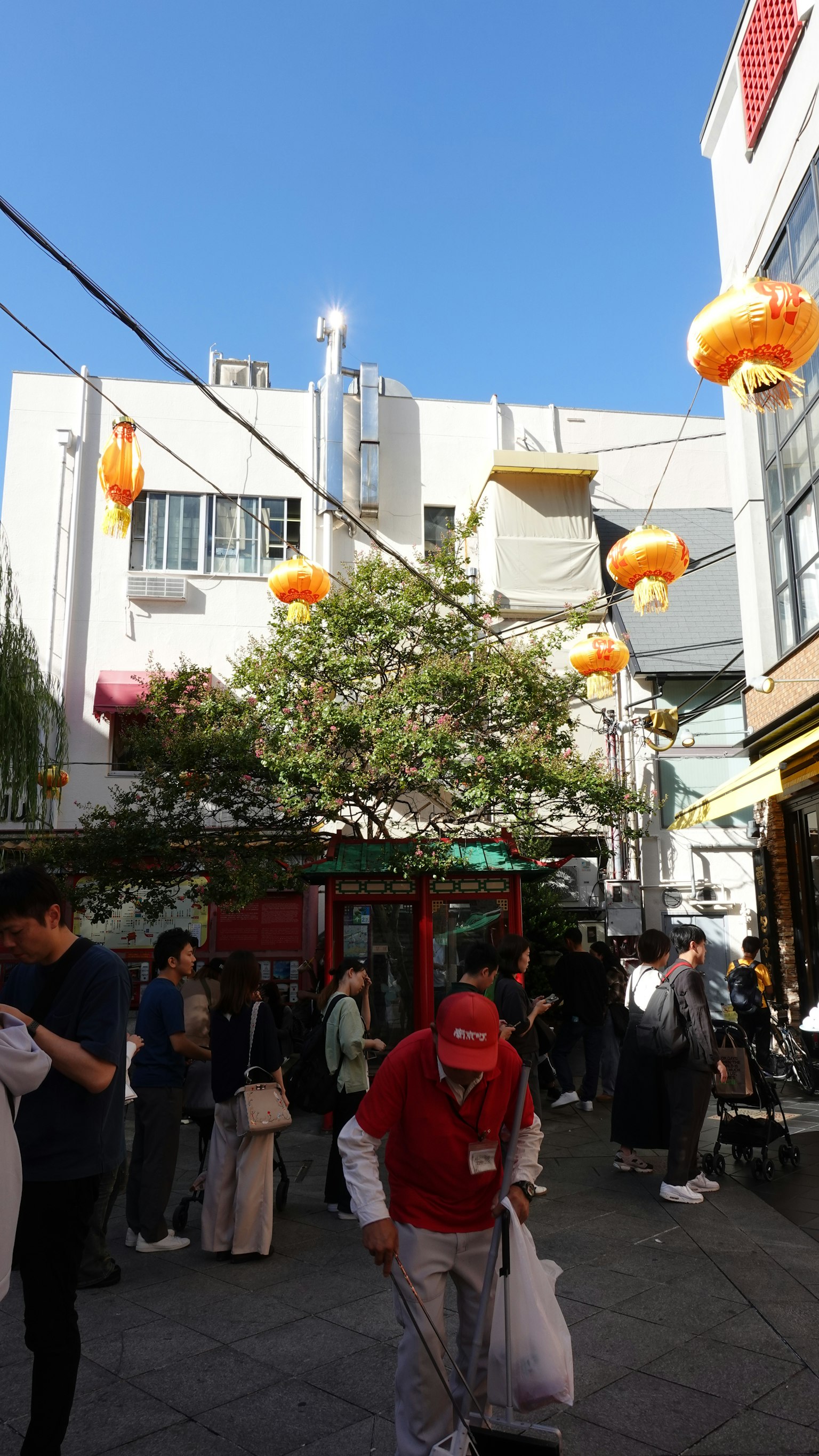 Una escena callejera vibrante bajo un cielo azul con faroles naranjas