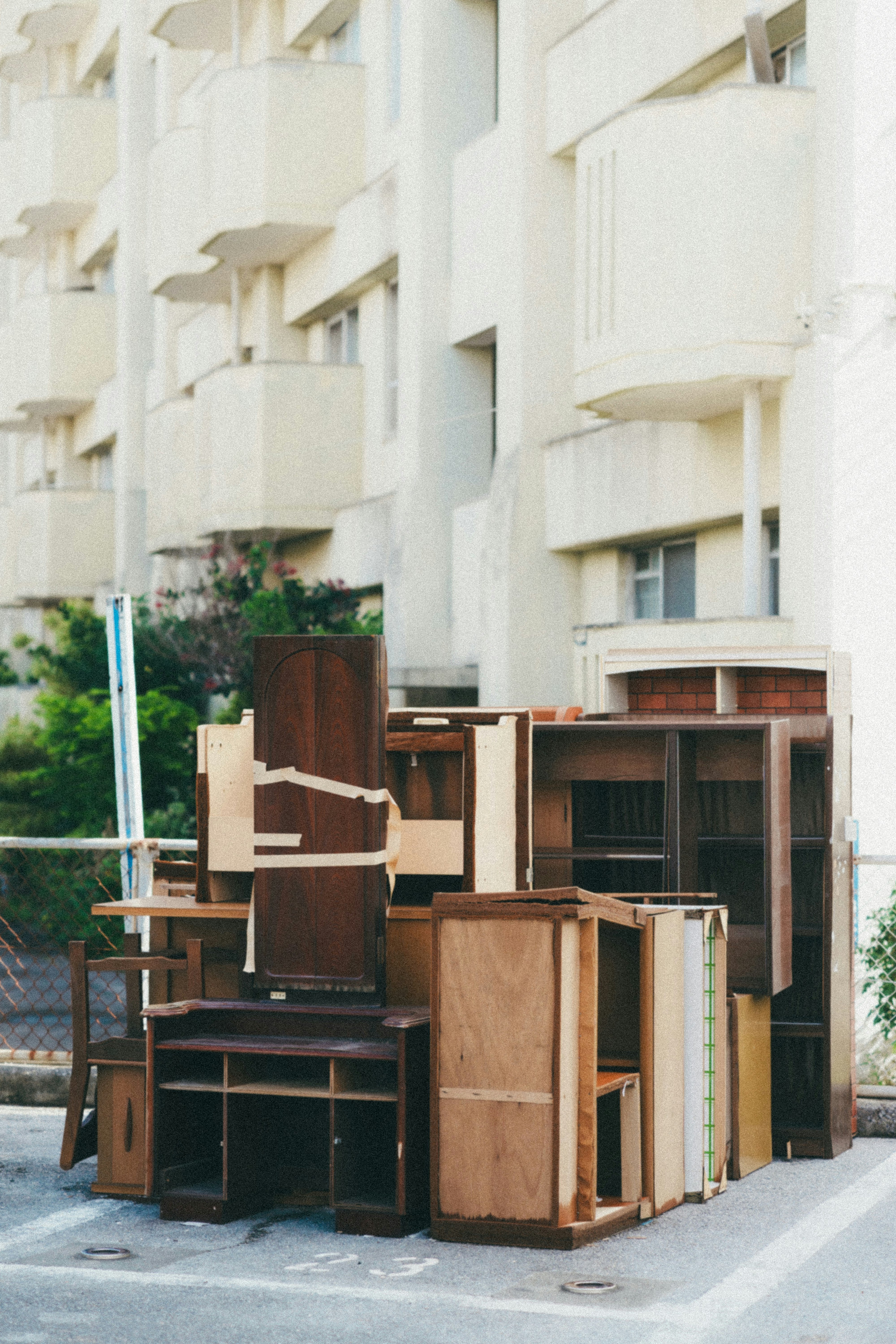 cardboard boxes and furniture stacked in a courtyard by white apartments