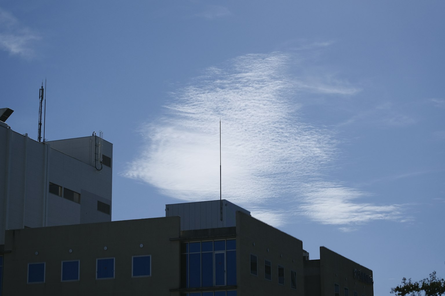 Formazione nuvolosa unica contro un cielo blu con parte di un edificio
