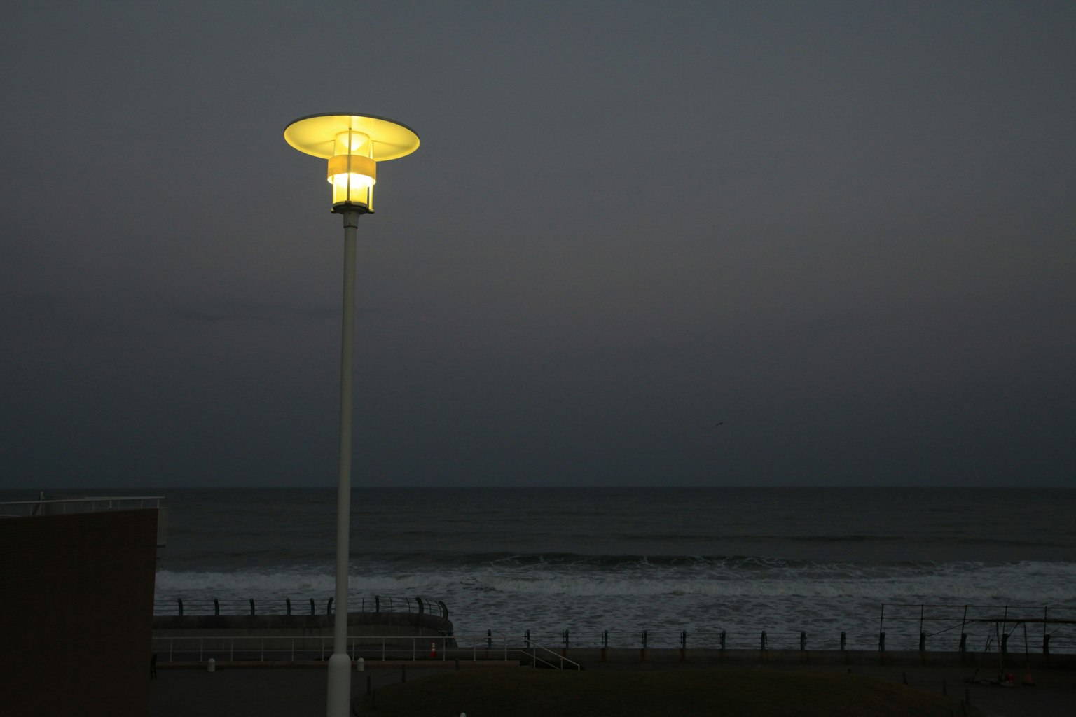 Lampu jalan terang di pantai pada malam hari dengan langit gelap