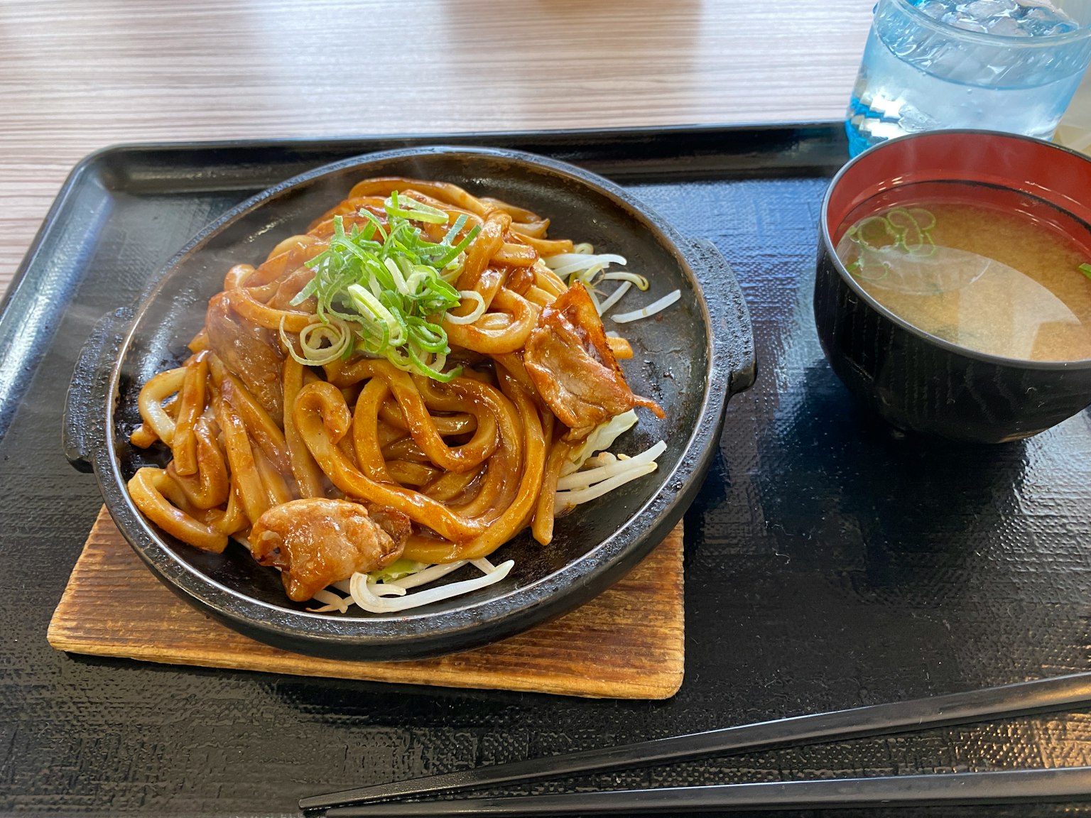 Udon goreng dengan daging sapi disajikan di atas piring panas dengan taburan daun bawang