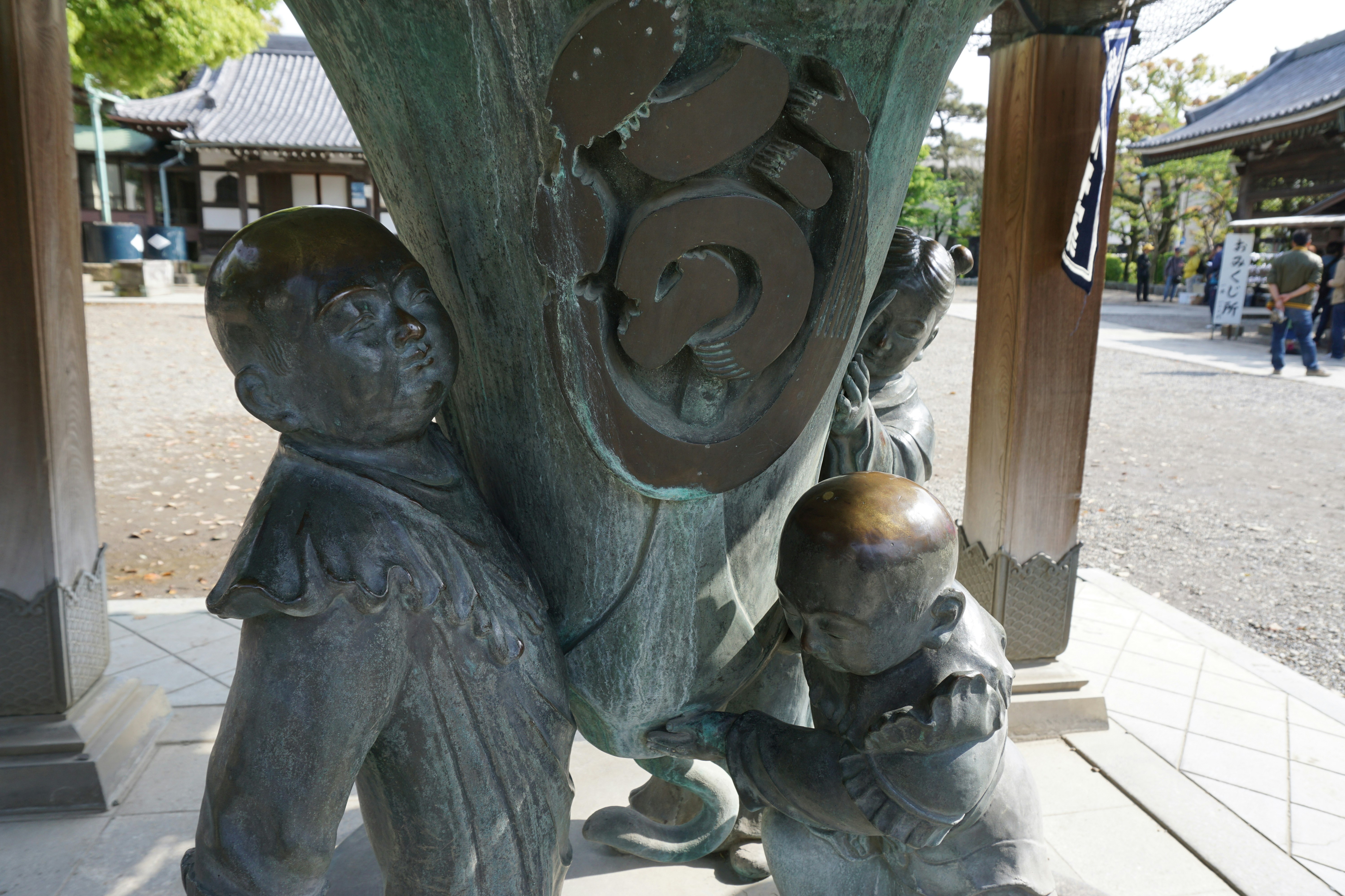 寺院の境内にある銅像の親子像と手水鉢