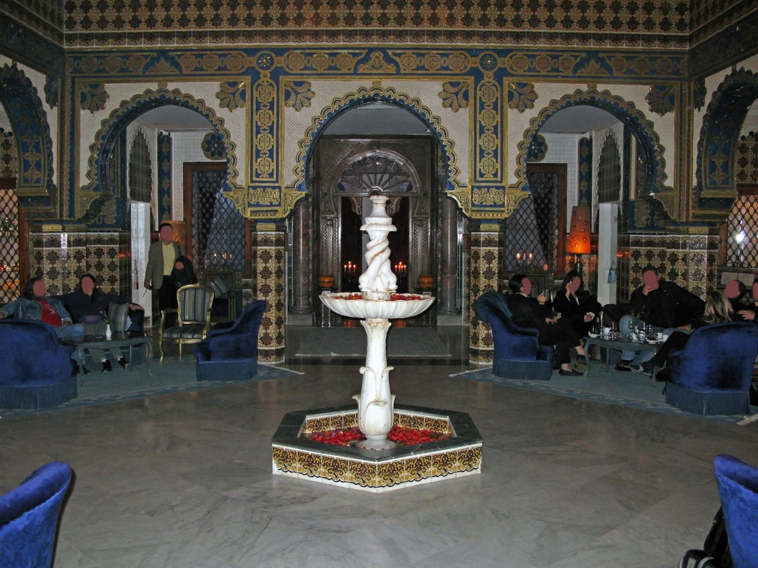 Moroccan-style interior featuring decorative tiles and arches A beautiful fountain is centrally located with blue sofas surrounding it