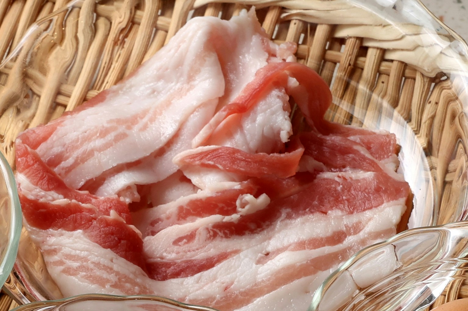 Thin slices of pork arranged in a bamboo basket