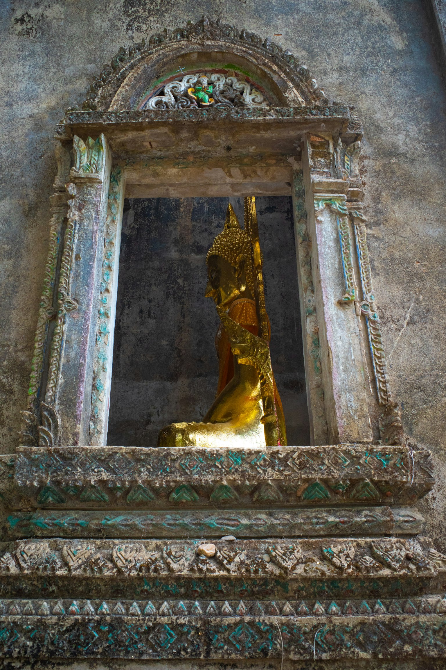 Estatua de Buda dorada en un nicho de un antiguo templo