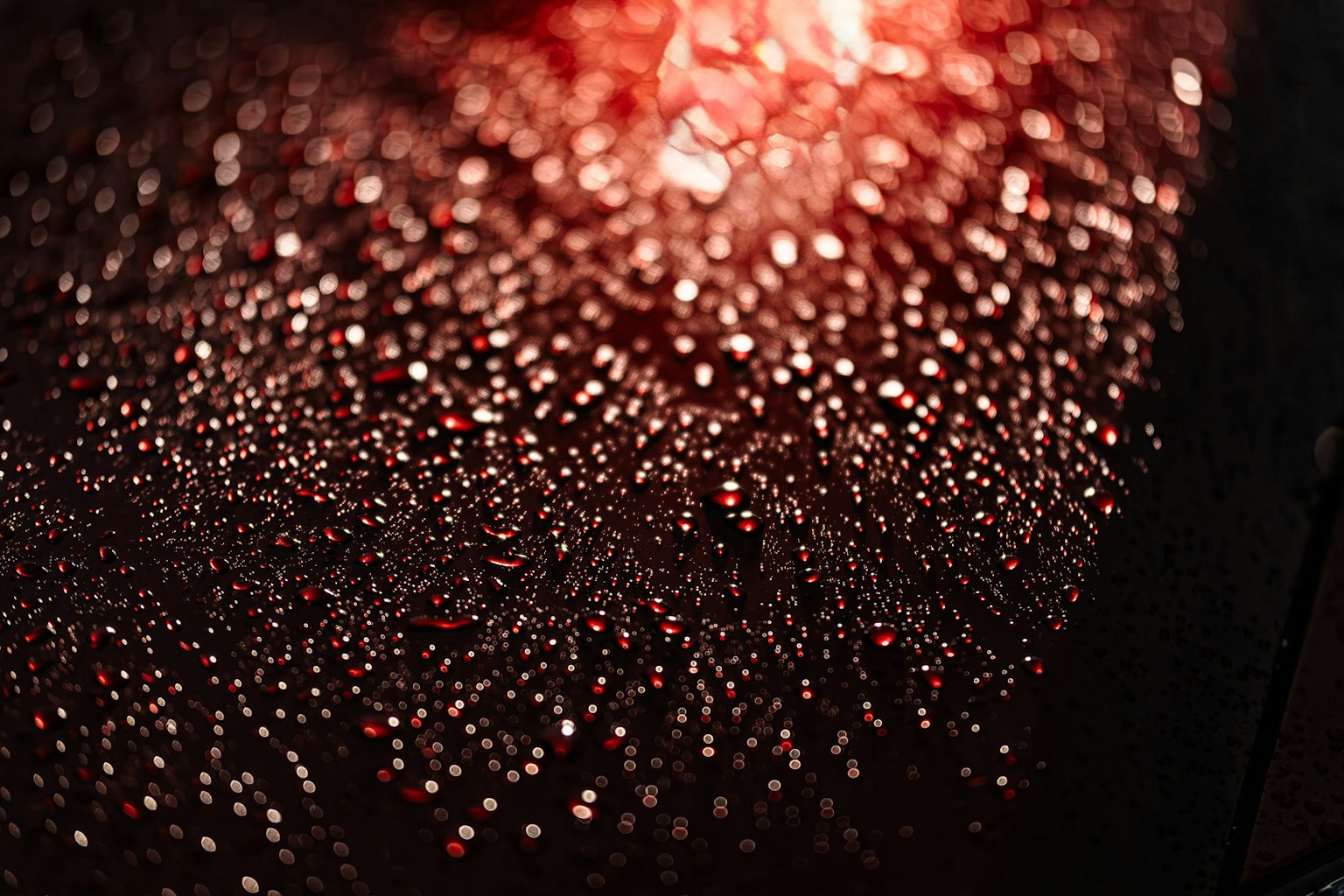 Superficie coperta di gocce luccicanti illuminate da luce rossa