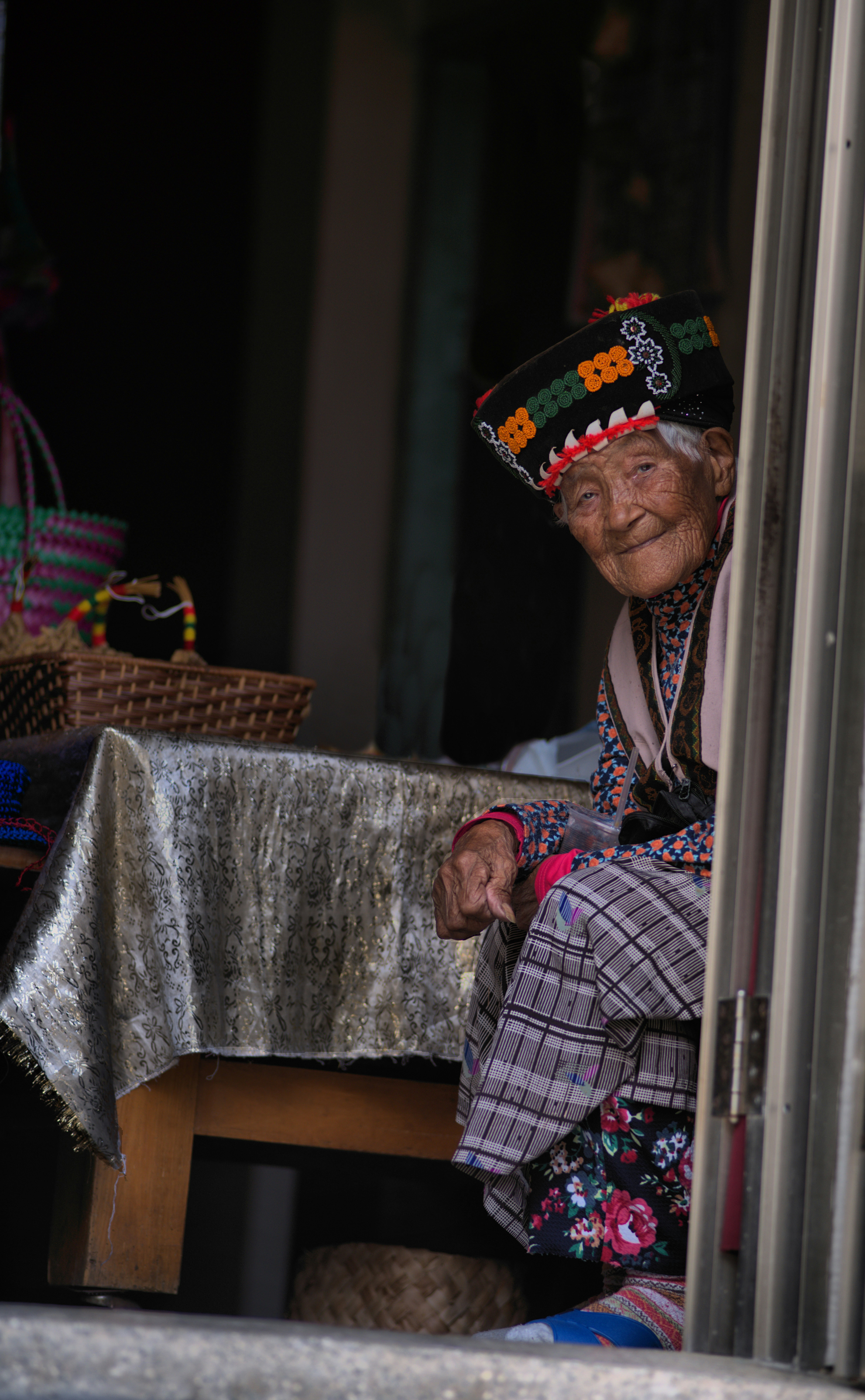 Une femme âgée en tenue traditionnelle vue à travers une fenêtre