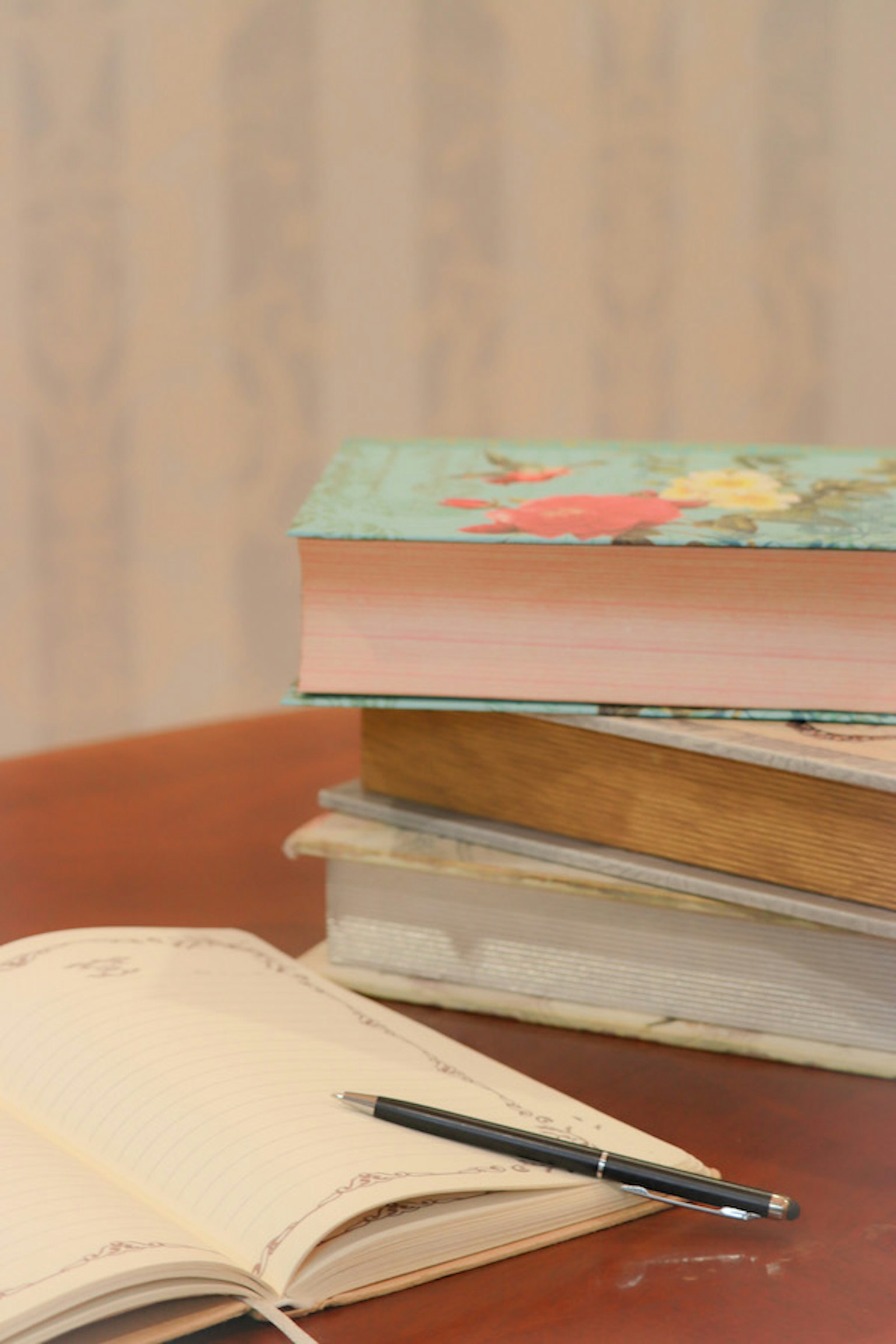 Seperangkat buku berwarna-warni di atas meja dengan buku catatan kosong dan pena