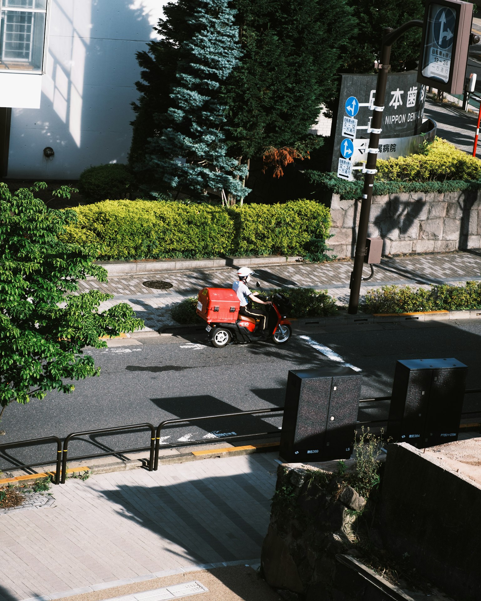 Red delivery bike driving on a tree-lined street
