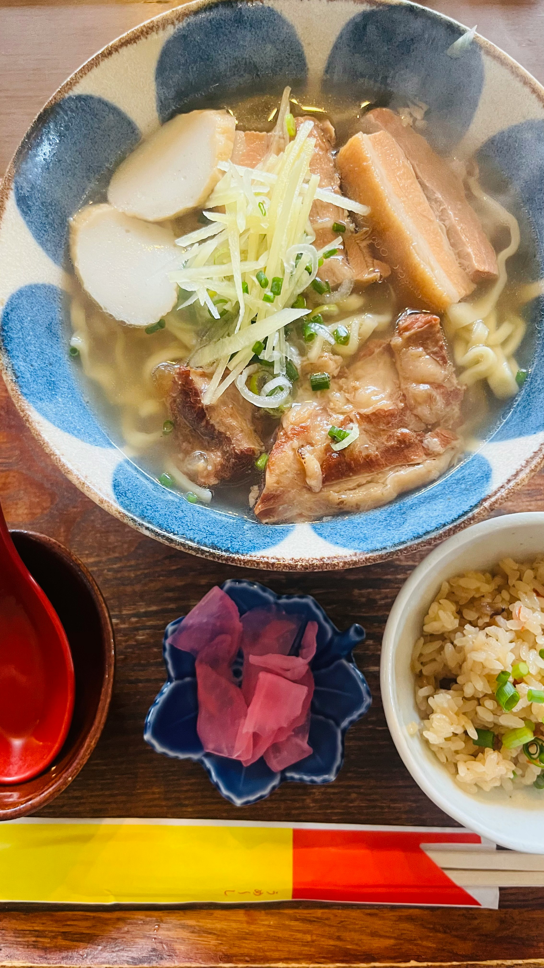 沖縄そばの器にのった豚肉と麺、薬味添え