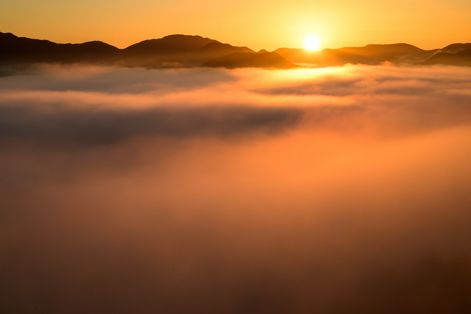 Sonnenaufgang über Bergen mit einem Nebelmeer