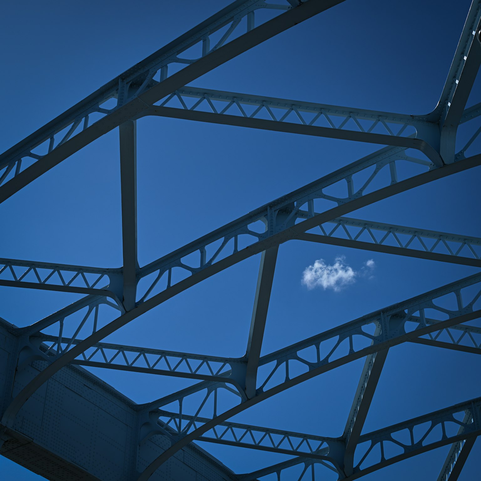 Struktur jembatan baja di bawah langit biru dengan awan
