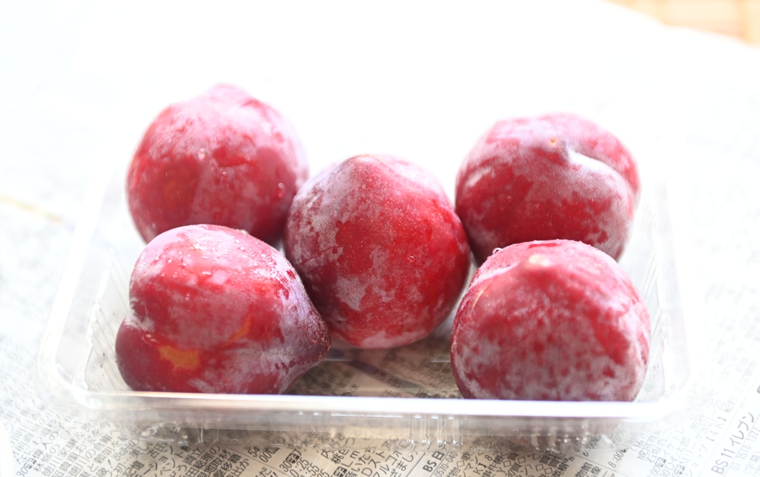 Red plums arranged in a clear container