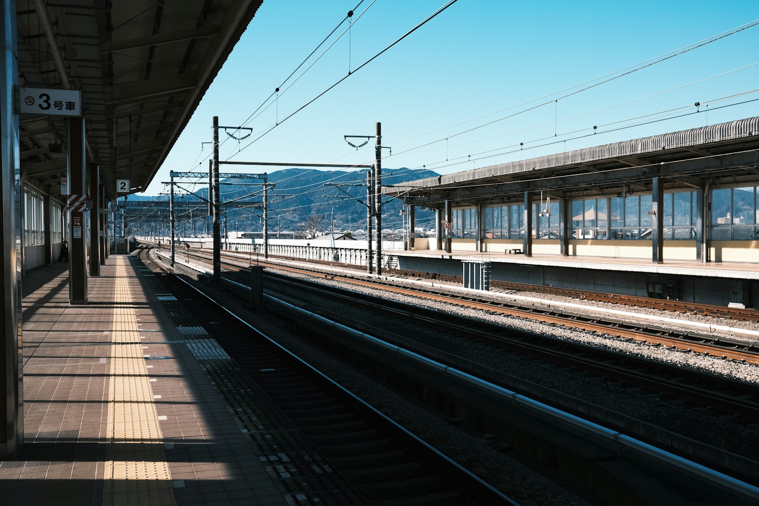 Plateforme de train calme et voies sous un ciel bleu
