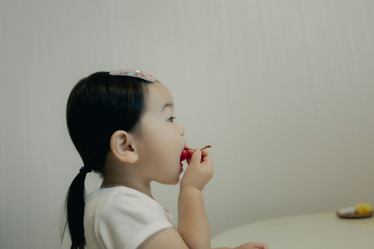Jeune fille mangeant un bonbon rouge de profil