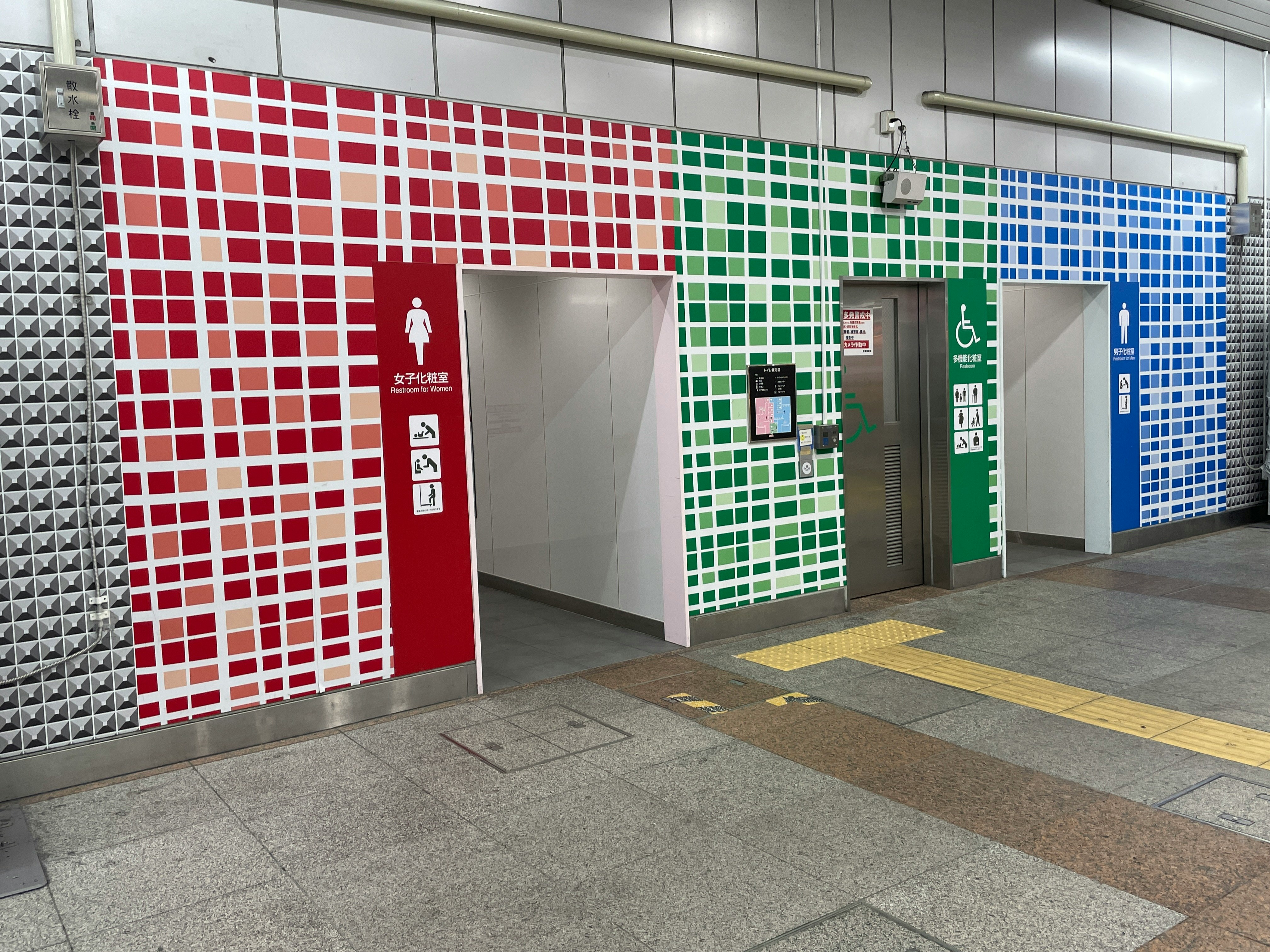 pasillo con azulejos coloridos y señales de salida de emergencia en una estación