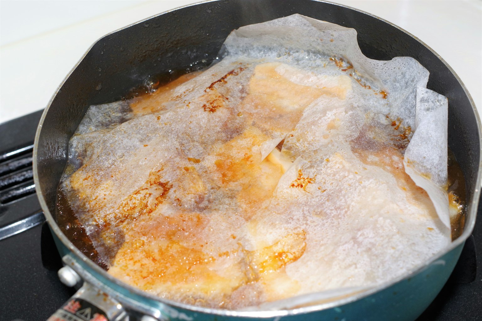 Cibo che frigge in una pentola con olio bollente e carta da forno sopra