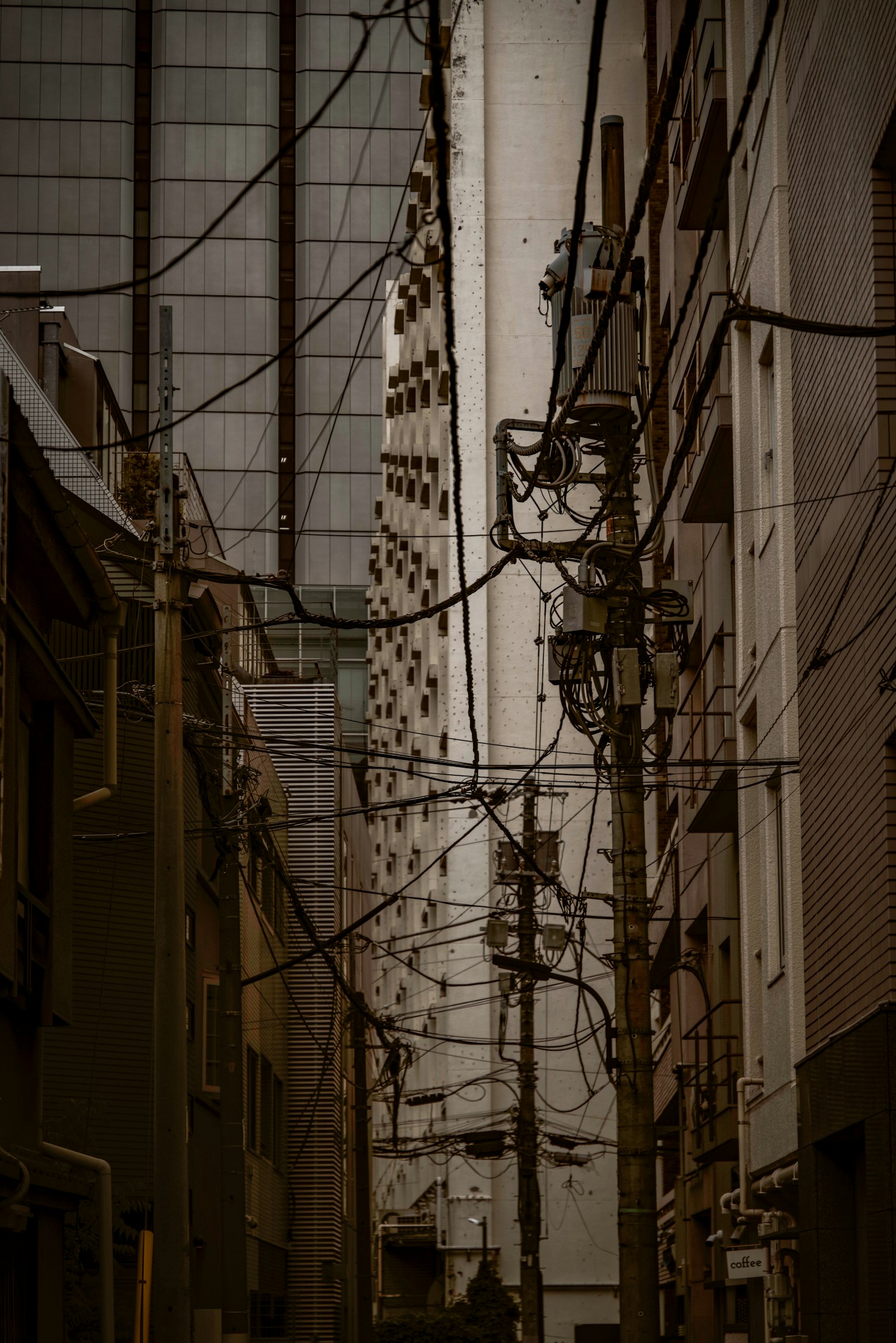 Callejón estrecho con cables eléctricos enredados y edificios altos