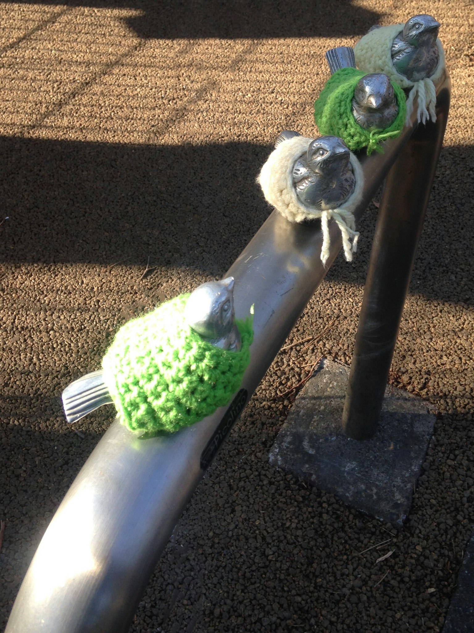 Bunte gestrickte Vögel mit Hüten auf einem Metallgeländer