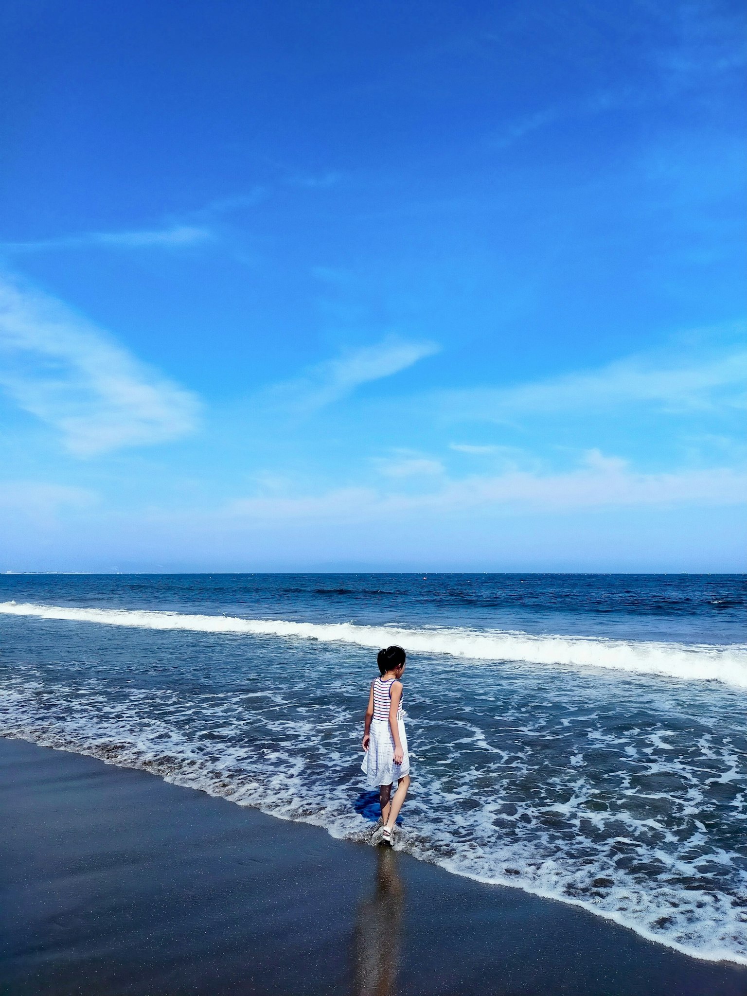 Donna che cammina lungo una bella spiaggia con cielo blu e onde