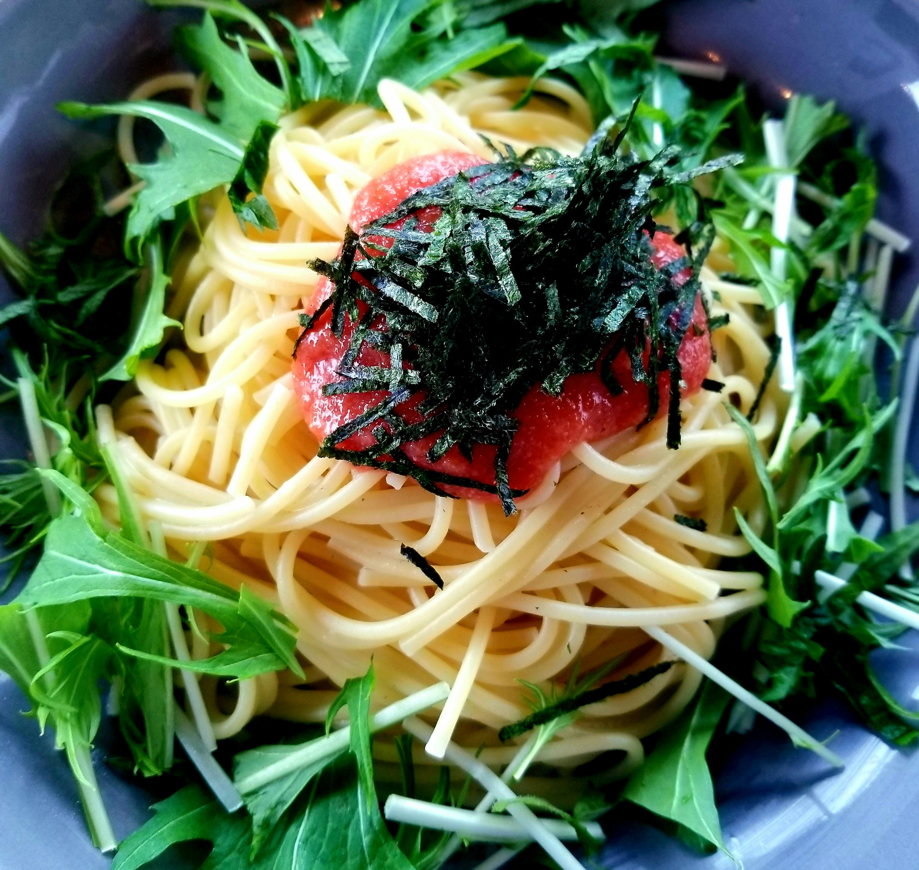 Espaguetis con tomate y algas, con rúcula en un plato