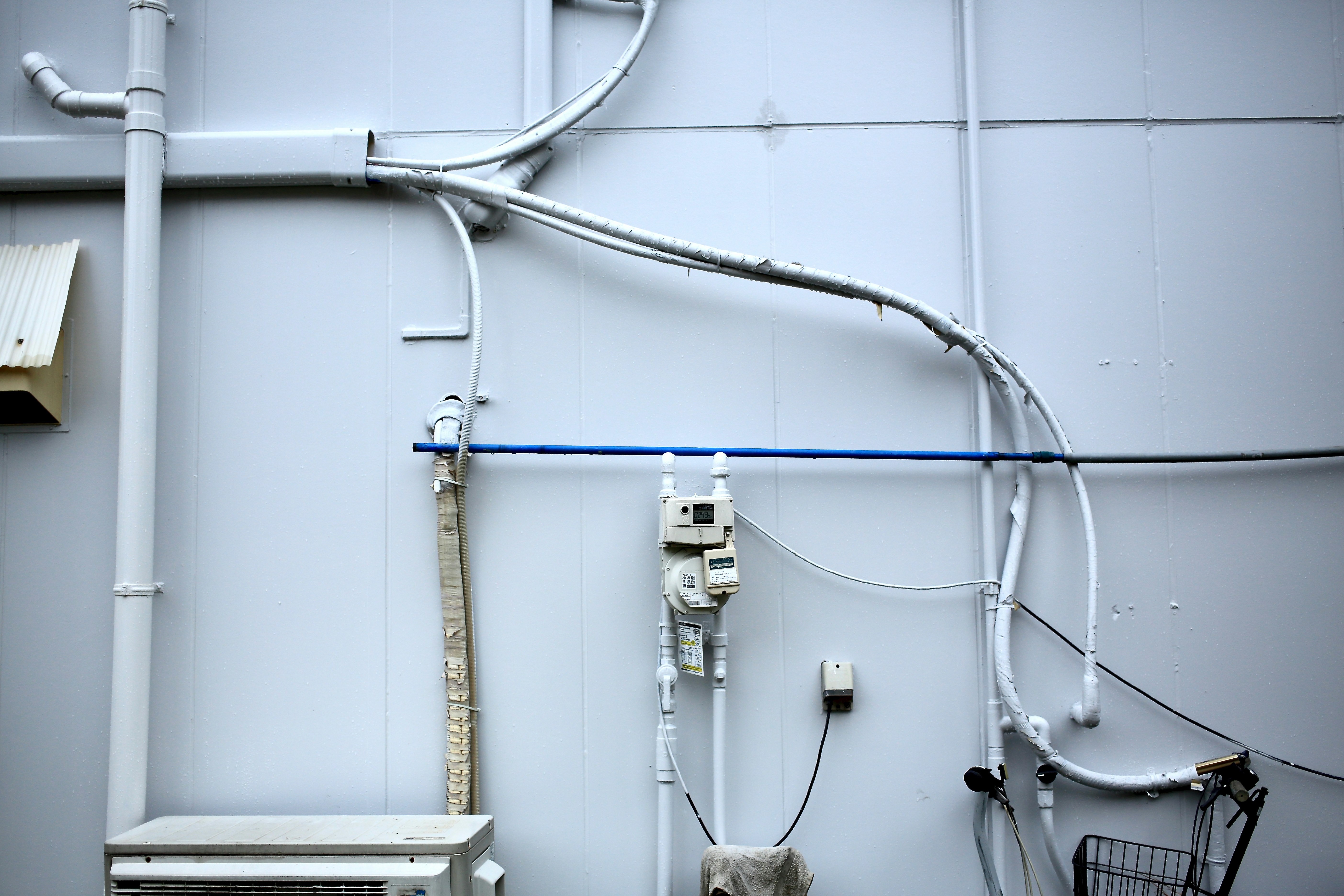 industrial equipment corner with white wall-mounted wiring and pipes
