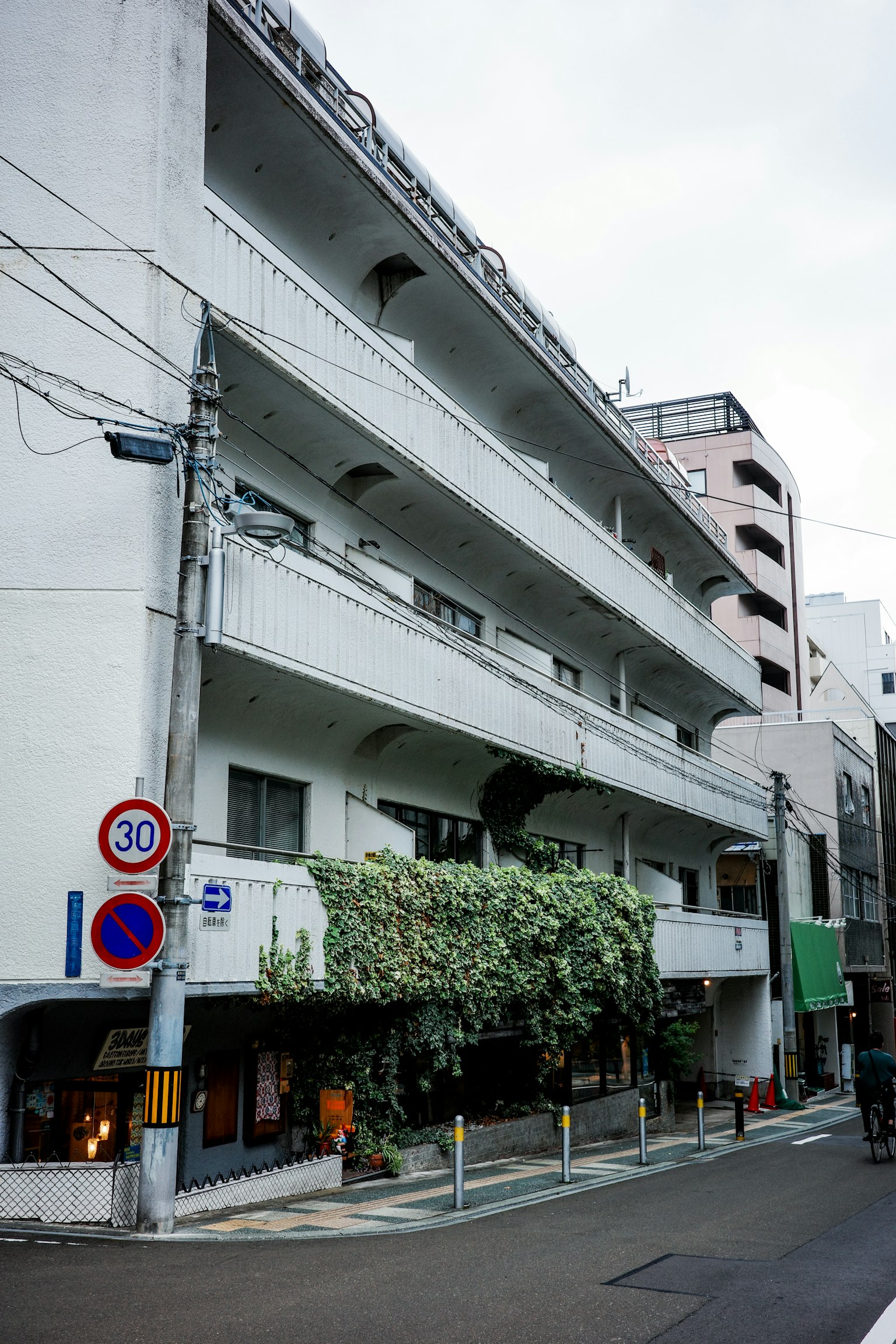 Street view featuring a four-story apartment building with a white facade
