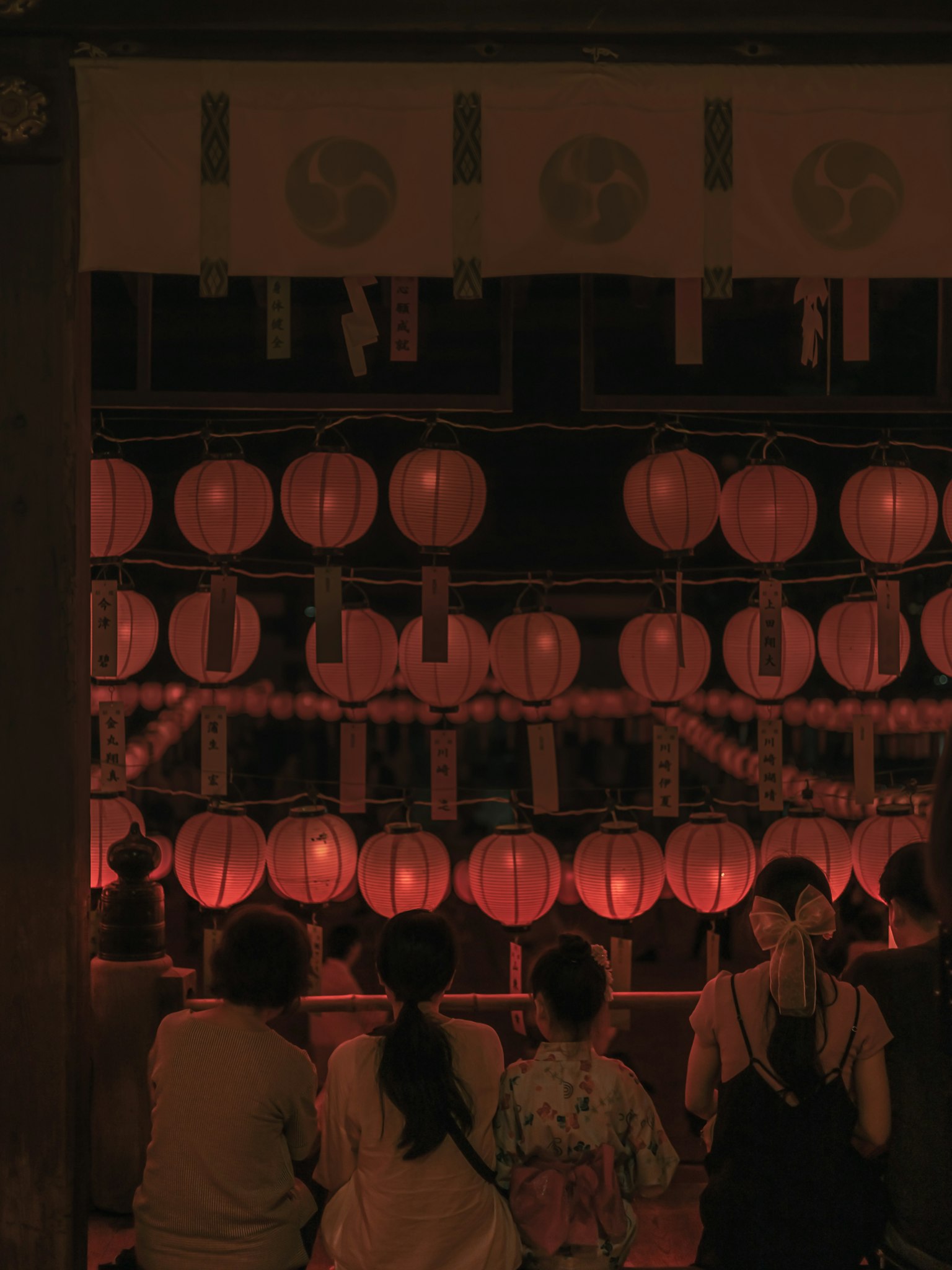 People admiring red lanterns in a nighttime setting