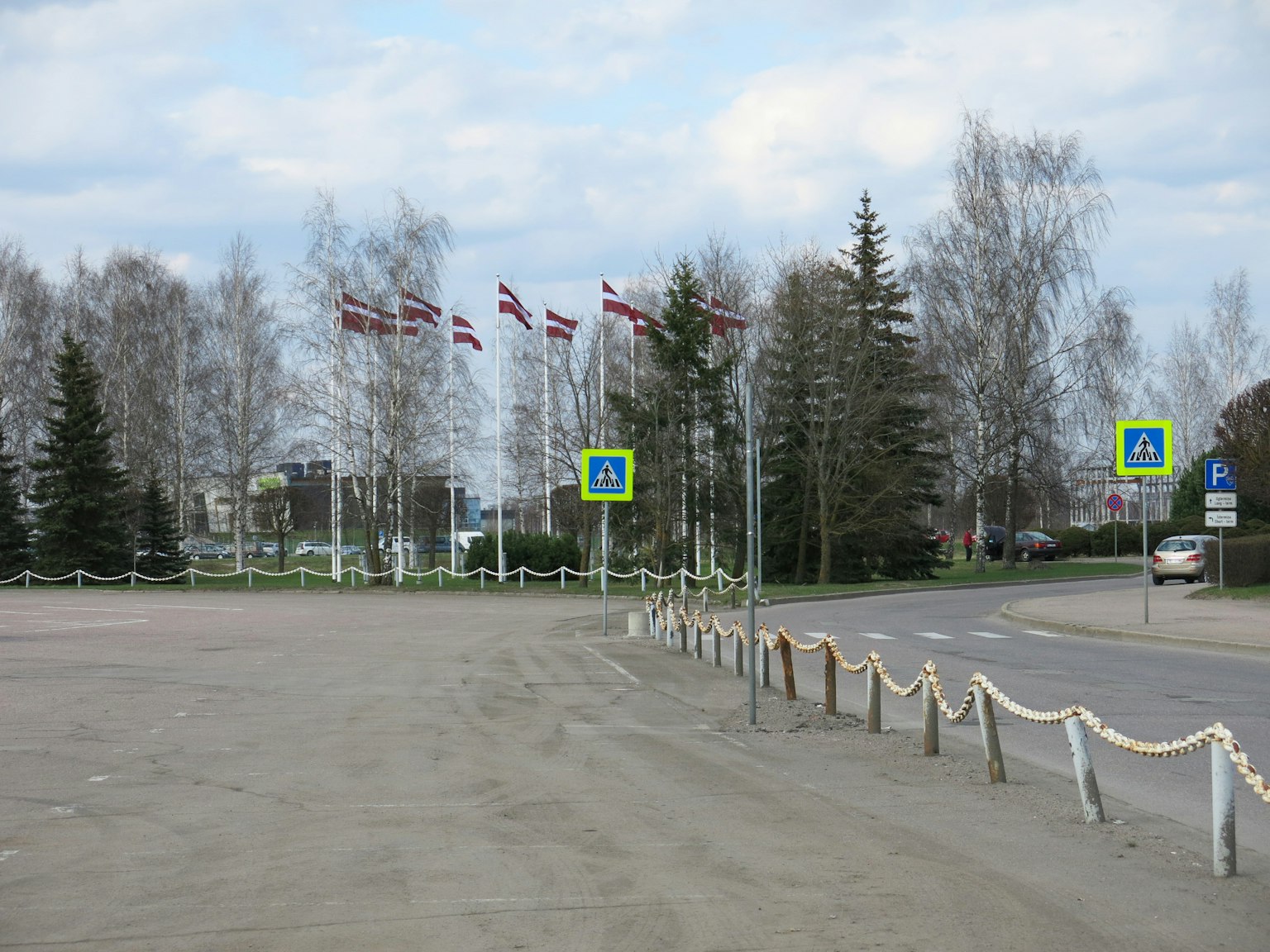 Cảnh công viên với cờ Latvia và biển báo giao thông dọc theo đường