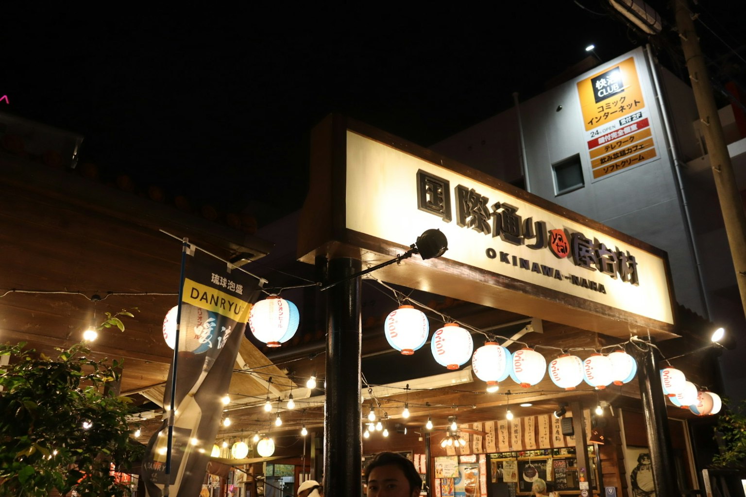 Cartel de restaurante japonés y farolillos iluminados por la noche