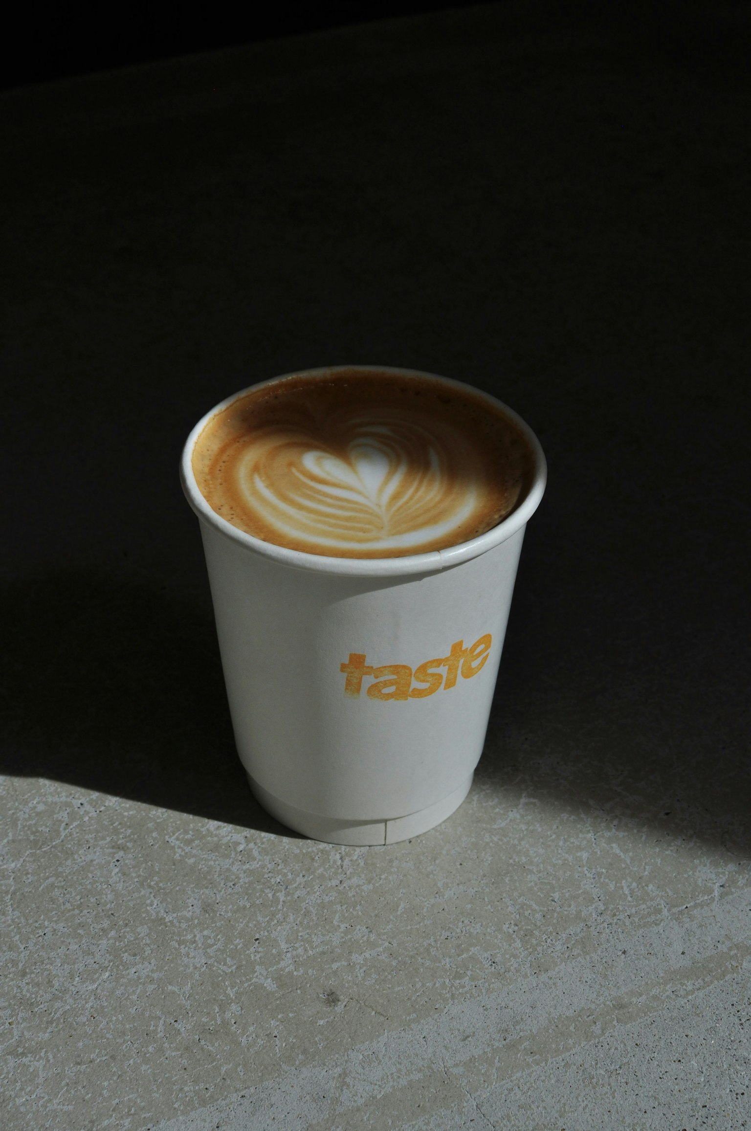 Seni latte dalam cangkir putih di permukaan abu-abu