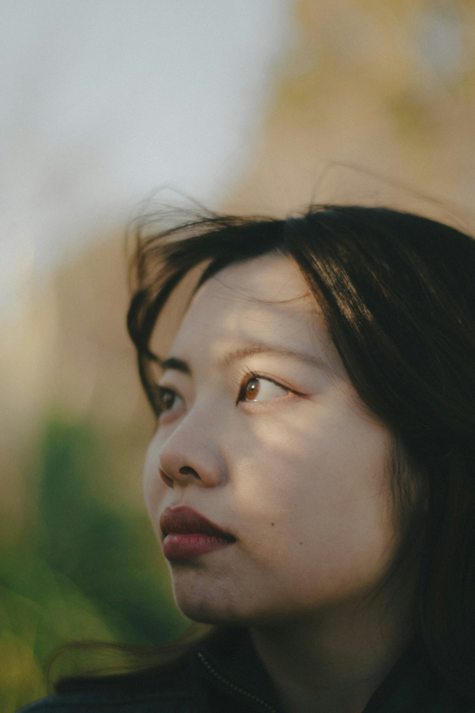 Gros plan sur le profil d'une femme avec des ombres sur son visage contre un arrière-plan naturel flou