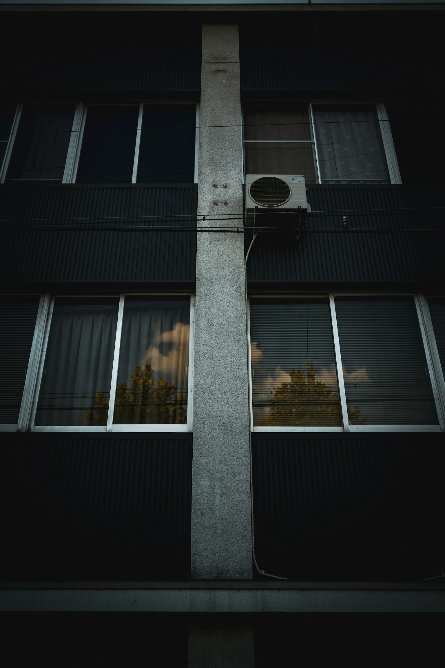 Façade d'un bâtiment avec un pilier en béton et une unité de climatisation