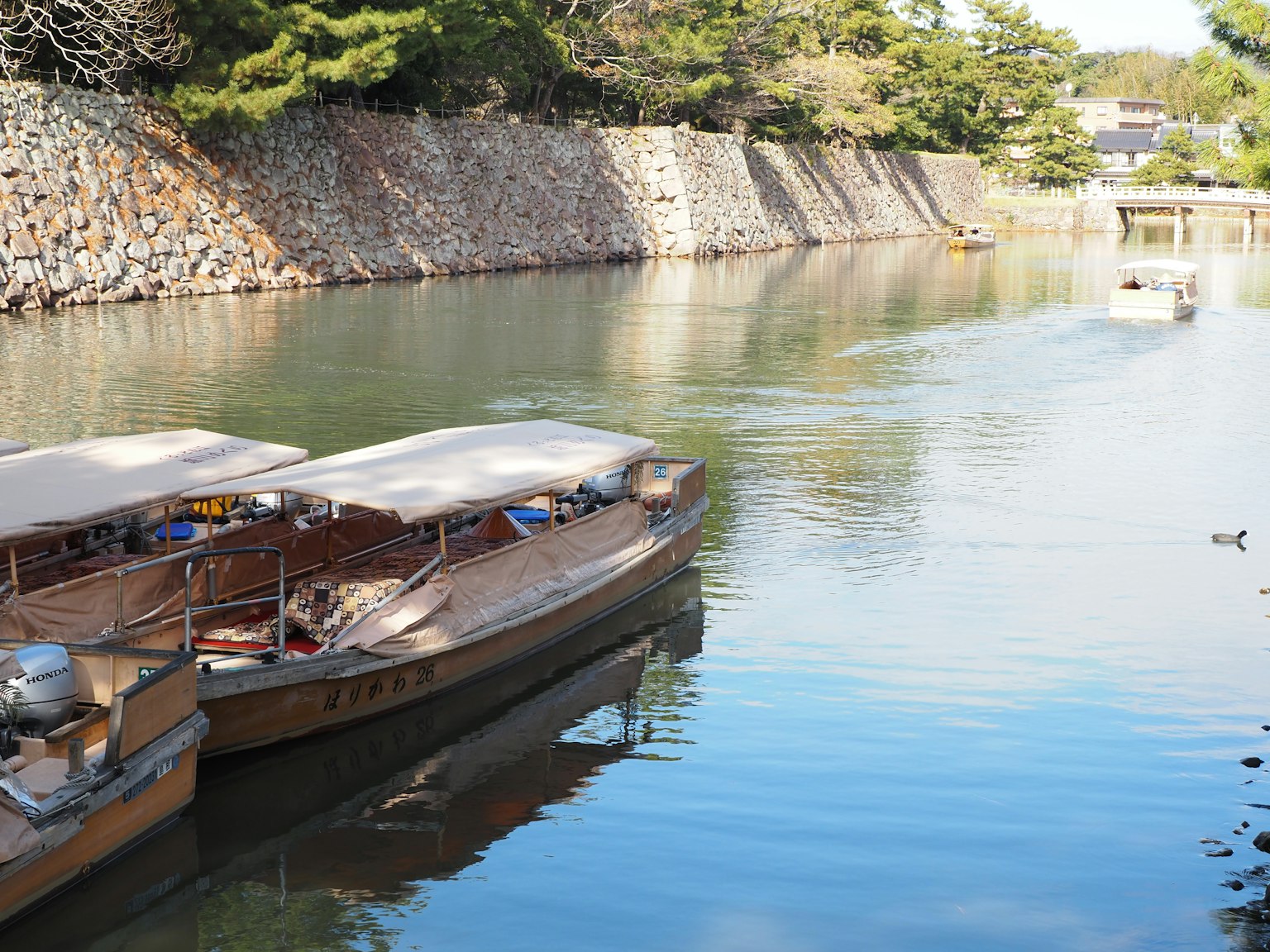 Traditionelle Boote an einem ruhigen Fluss mit einer Steinmauer