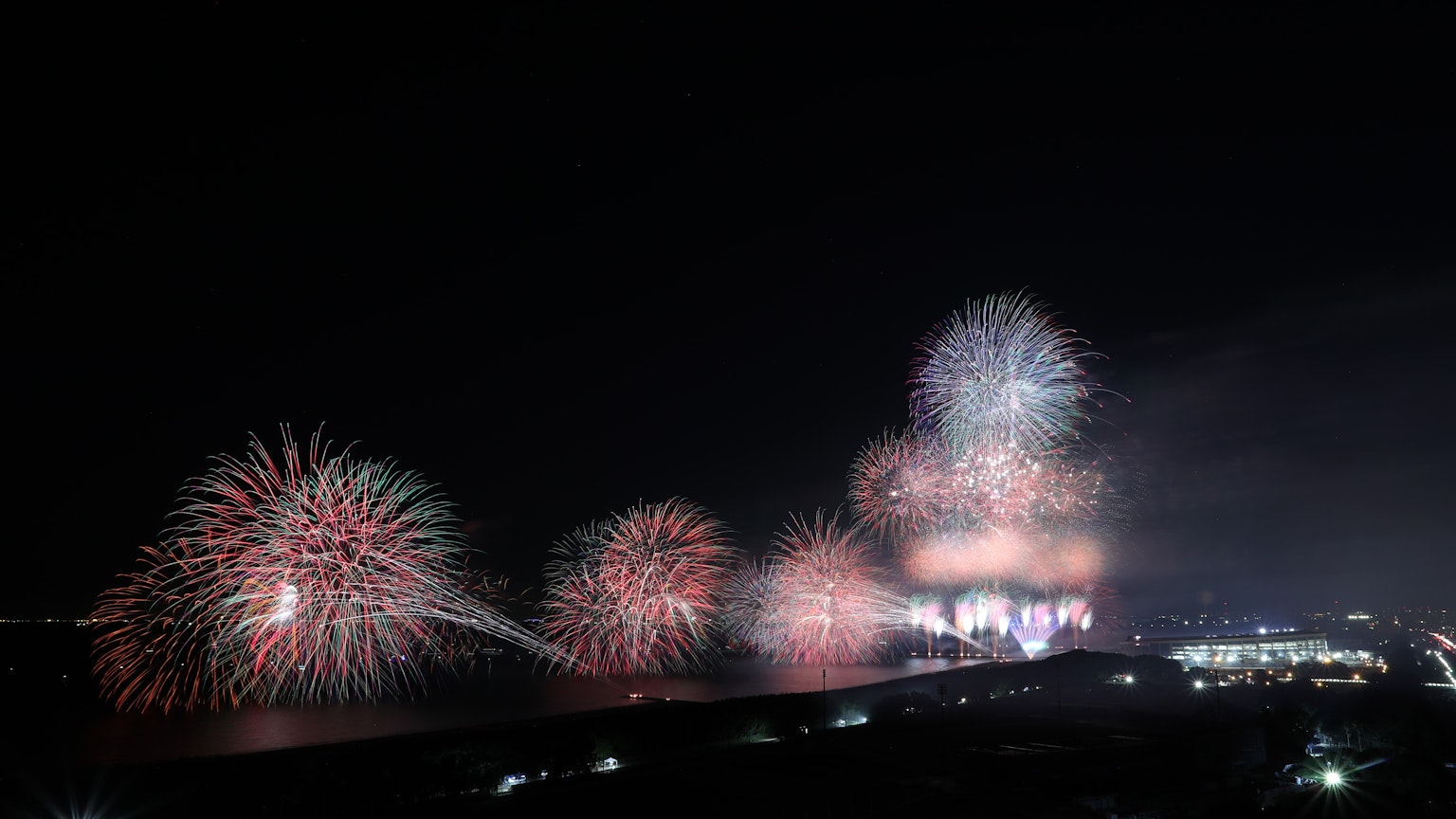 Spettacolo di fuochi d'artificio colorati che illumina il cielo notturno riflesso sull'acqua